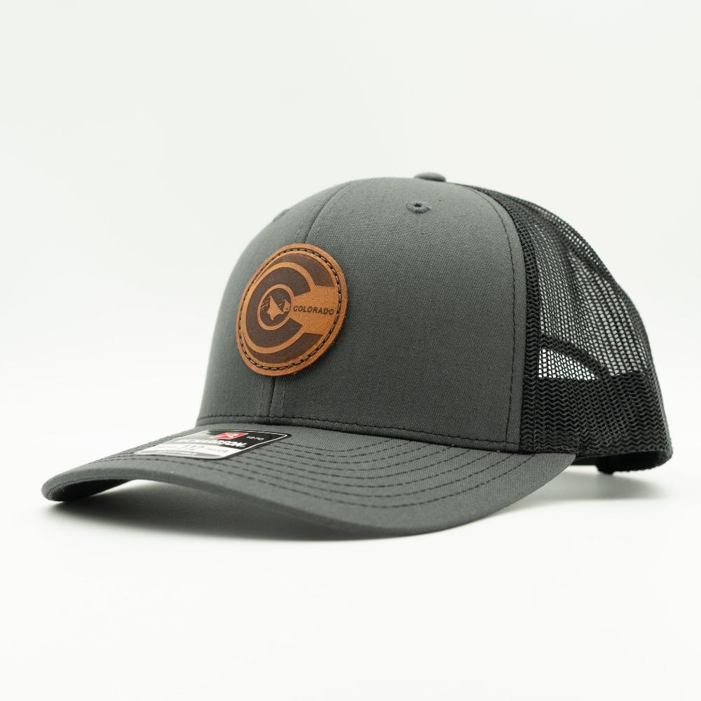 Side view of charcoal and black Richardson 112 Colorado flag leather patch trucker hat with mesh back and curved brim.