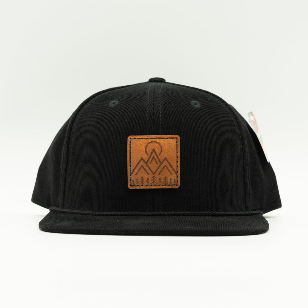 Front view of Moonlite Mountain leather patch rope hat on black Richardson 253 corduroy, showing square mountain patch, vintage rope, and flat bill.