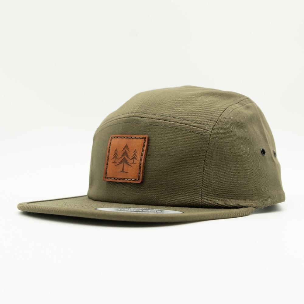 Side view of olive Yupoong 7005 Three Lil Pines hat, showing soft five panel shape, flat bill, and sewn real leather pine tree patch.