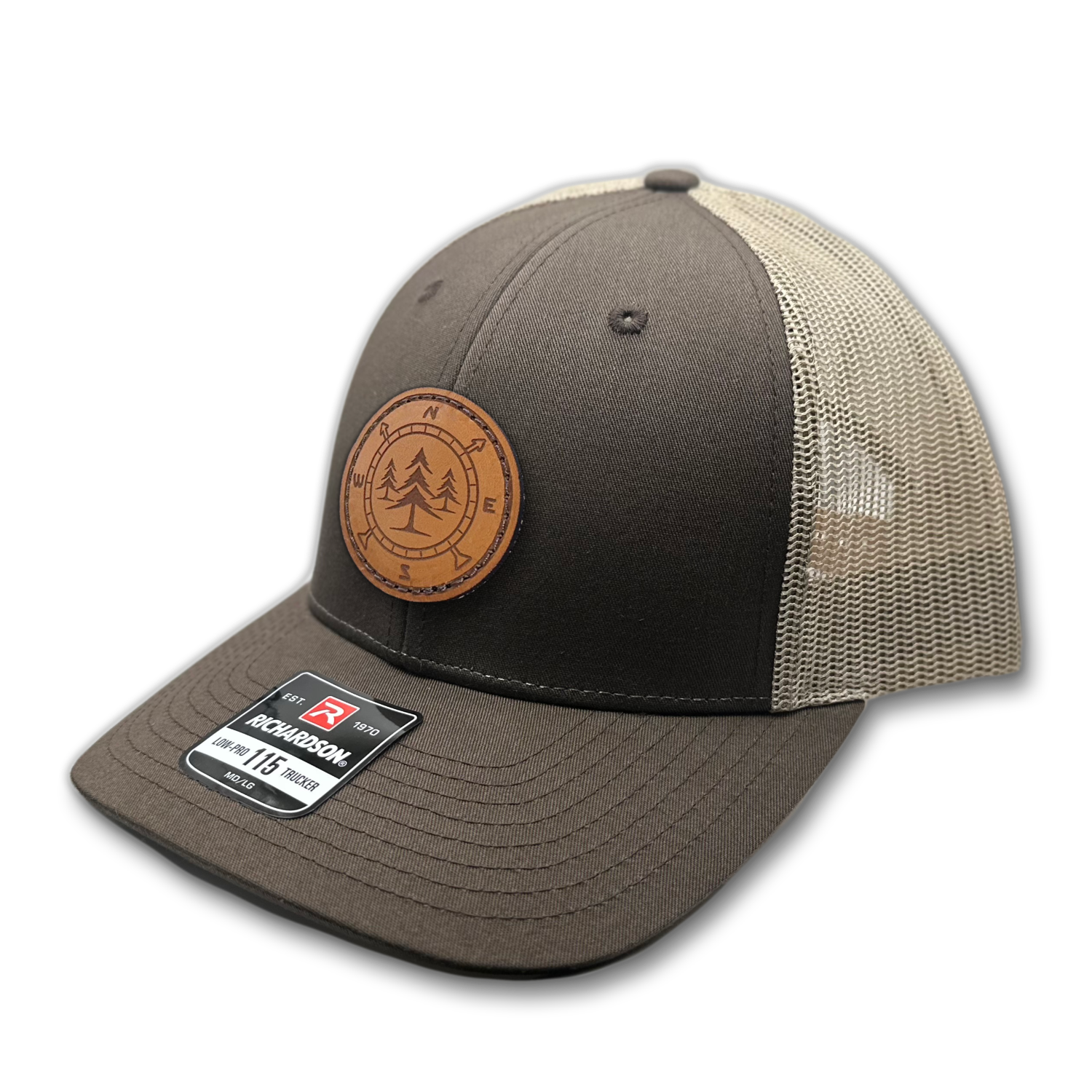 A high-quality leather patch hat named Lost Pines, showcasing a distinctive compass and pine trees design on a circular leather patch. Made in the USA, this hat features genuine leather craftsmanship and is affixed to a brown/khaki Richardson 115 low profile SnapBack hat. Available in small and m/l sizes and various colors, this unique hat is inspired by the picturesque mountains of Colorado. Perfect for hat enthusiasts and those seeking stylish leather patch designs.
