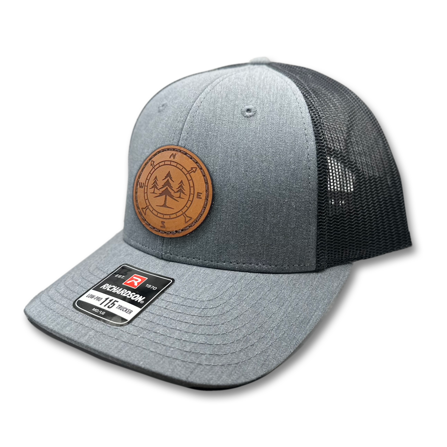 A high-quality leather patch hat named Lost Pines, showcasing a distinctive compass and pine trees design on a circular leather patch. Made in the USA, this hat features genuine leather craftsmanship and is affixed to a Heather grey/charcoal Richardson 115 low profile SnapBack hat. Available in small and m/l sizes and various colors, this unique hat is inspired by the picturesque mountains of Colorado. Perfect for hat enthusiasts and those seeking stylish leather patch designs.