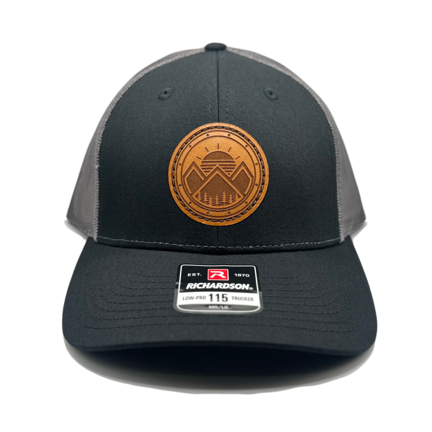 A unique leather patch hat named Modern Mountains, showcasing a design with 3 mountain peaks, a sunrise, pine trees, and decorative border on a circular patch. Crafted in the USA, this authentic leather patch is skillfully sewn onto a Richardson 115 low profile SnapBack hat. Available in small and m/l sizes in the Richardson 115 style, and in multiple colors on the Richardson 112. Inspired by the majestic mountains of Colorado, this hat is perfect for those who appreciate high-quality leather patch designs.