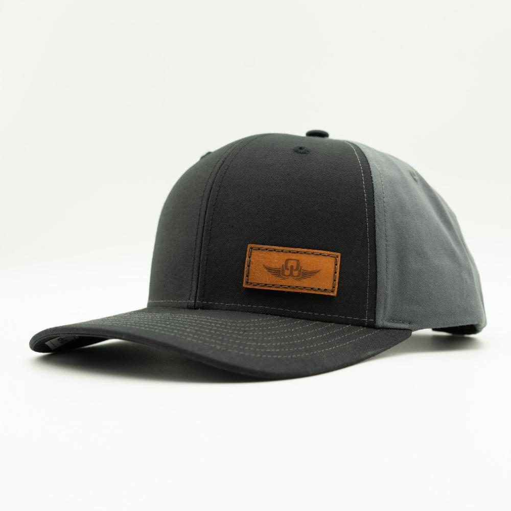 Side view of black/charcoal Richardson 312 hat with Spread Your Wings leather patch, full-fabric construction and curved visor.
