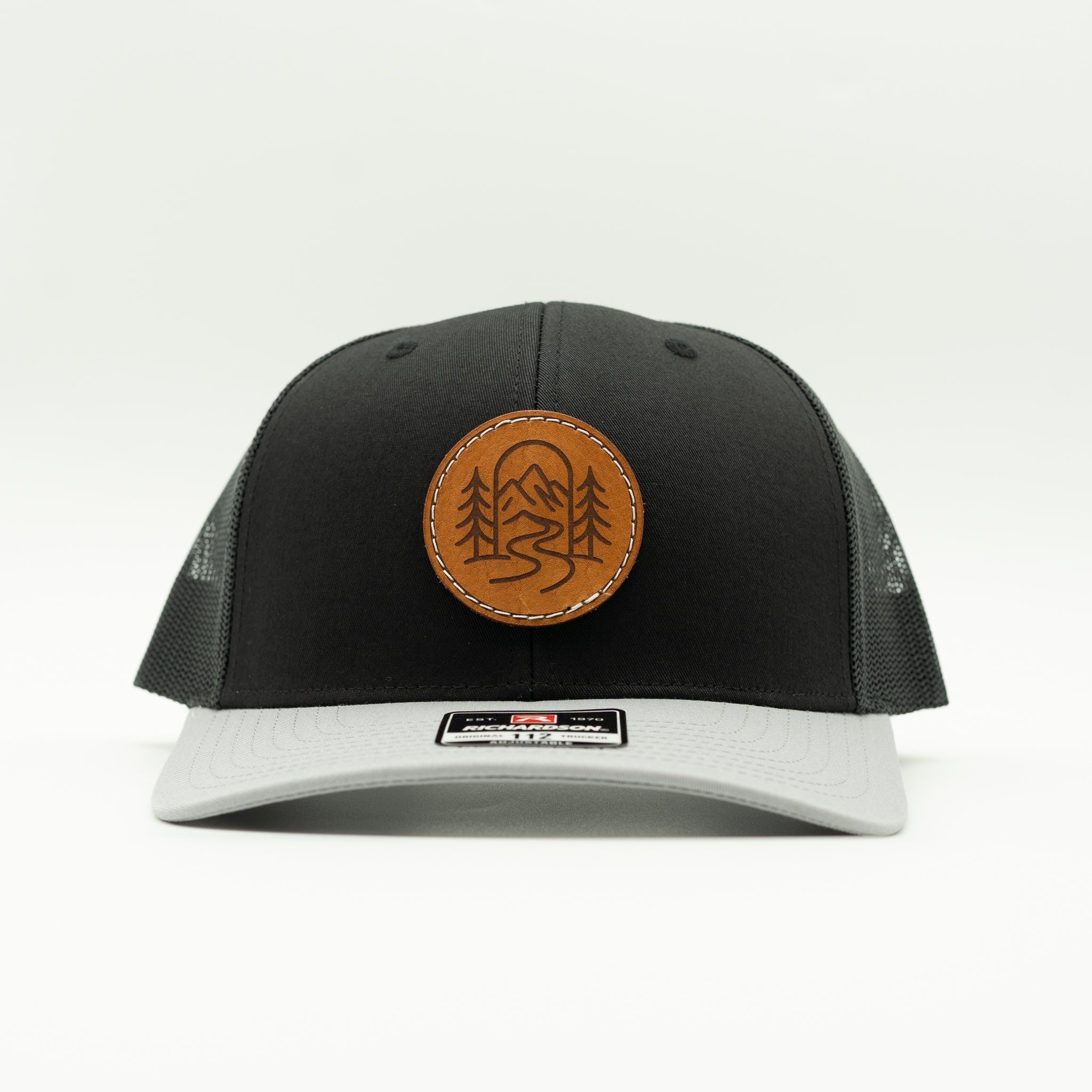 Front view of black and grey Richardson 112 The Passage hat with round veg tan leather mountain design.