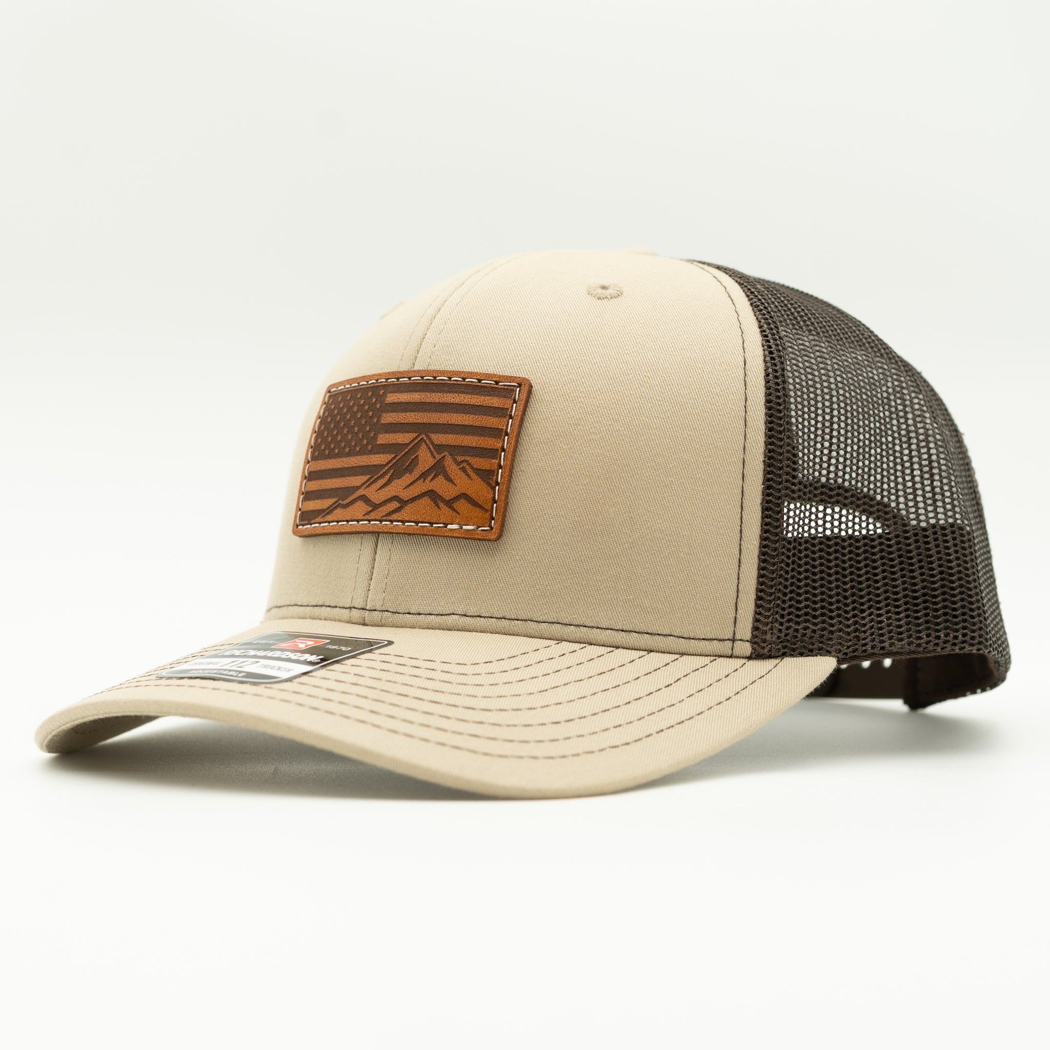 Side profile of American Range American flag leather patch hat on khaki and brown Richardson 112 trucker, showing patch, curved bill, mesh back, and snapback, an outdoors inspired patriotic mountain hat for fishing, hiking, and daily wear.
Color: Khaki/Coffee