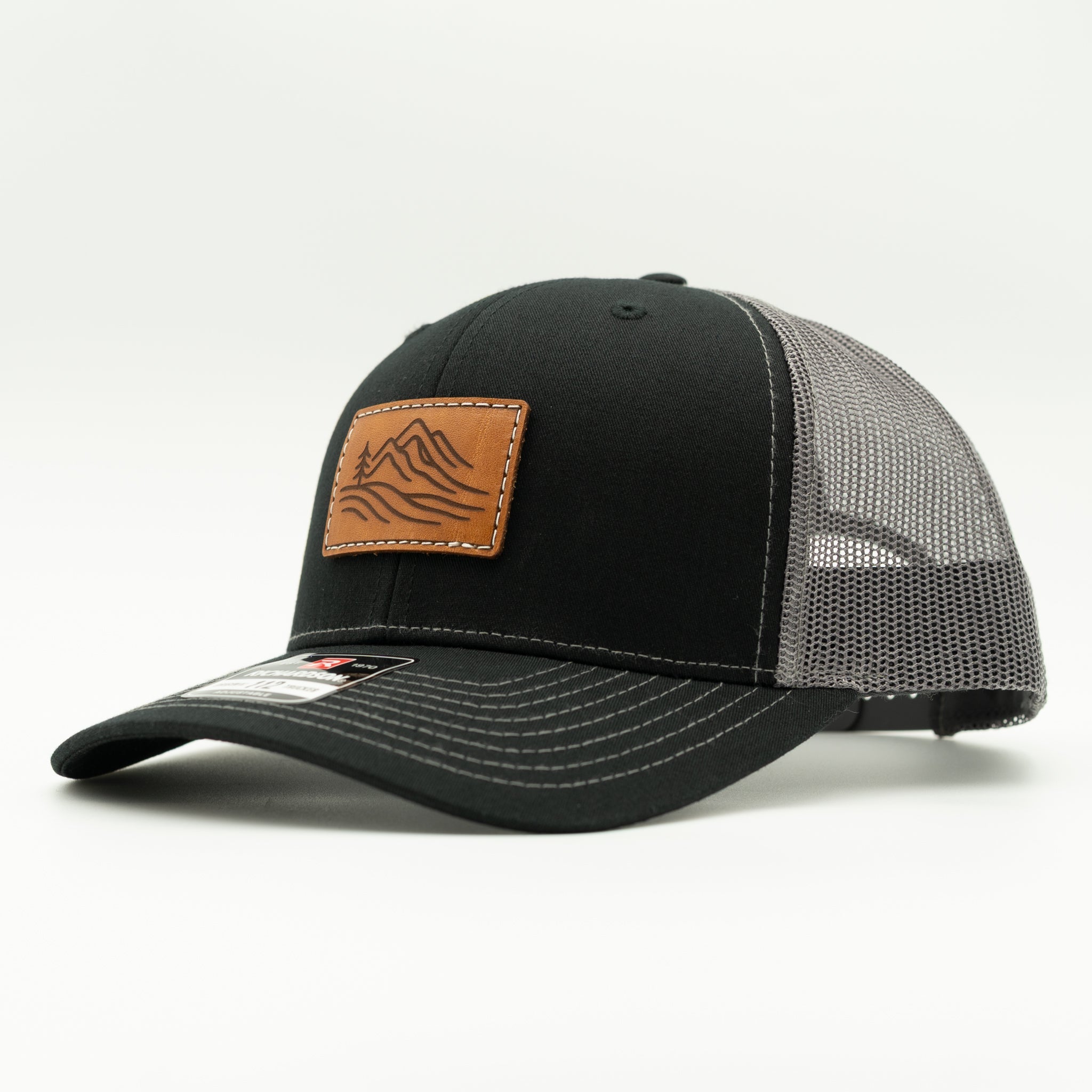 Side view of black and charcoal Richardson 112 Driftline hat with veg-tan leather mountain patch and curved visor.
Color: Black/Charcoal
