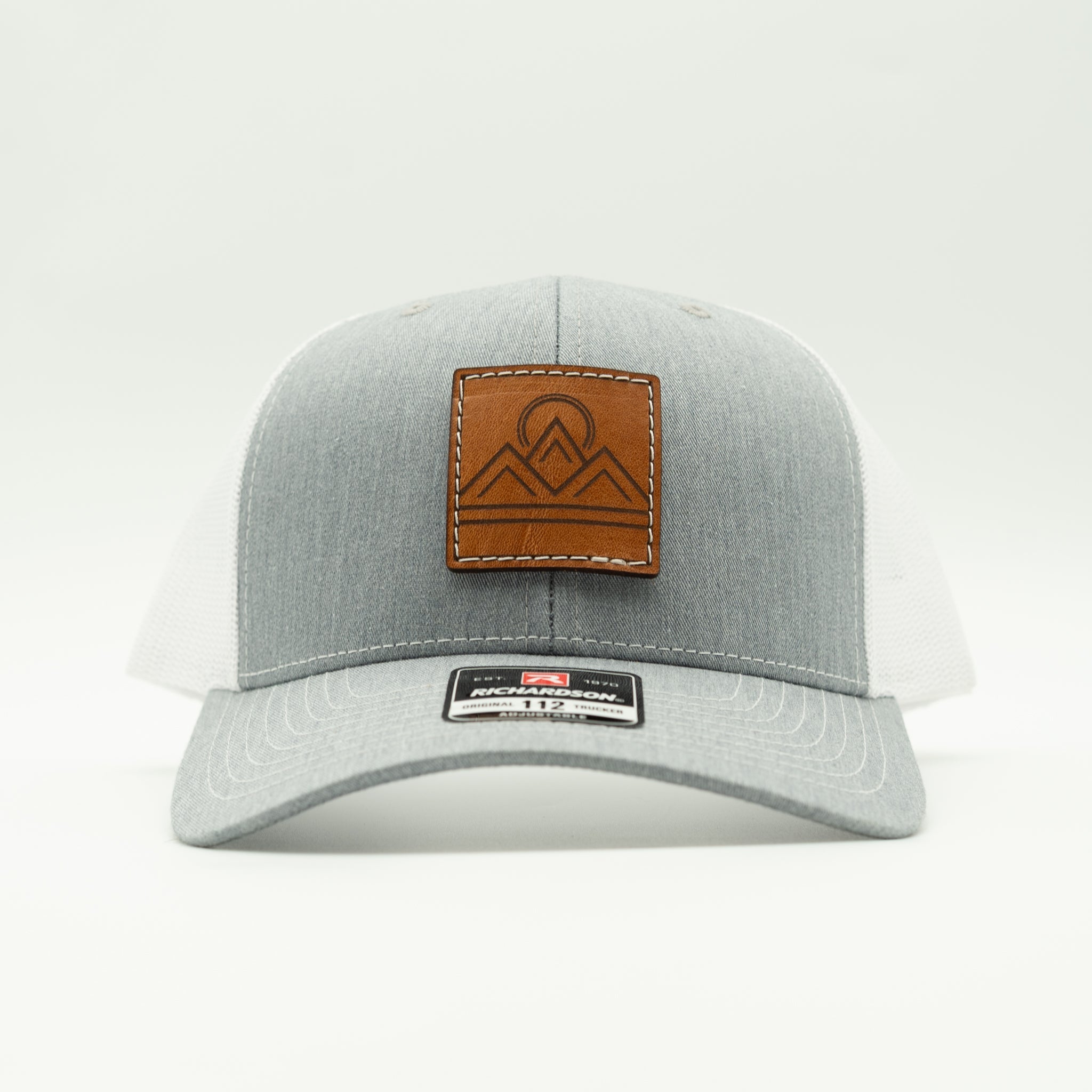 Front view of Lunar Ridge heather grey and white Richardson 112 trucker hat with veg tan leather mountain patch
Color: Heather Grey/White