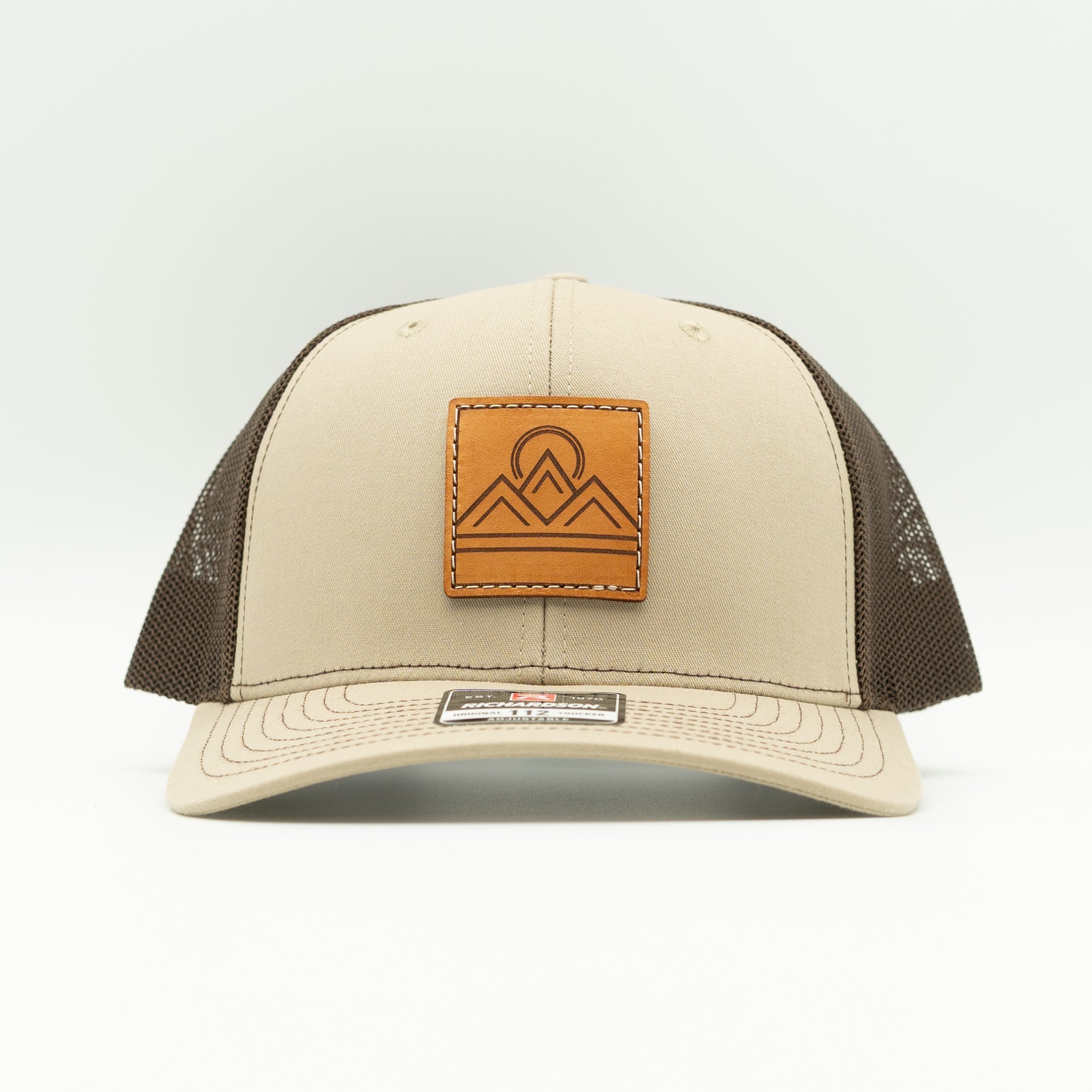 Front view of Lunar Ridge khaki and coffee Richardson 112 trucker hat with sewn leather mountain patch
Color: Khaki/Coffee