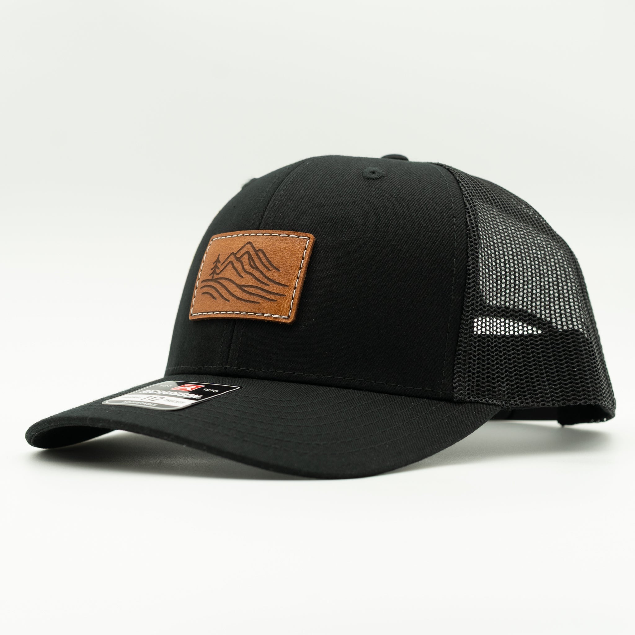 Side view of black Richardson 112 Driftline leather patch hat, mountain range design, mesh back trucker for everyday wear.
Color: Solid Black