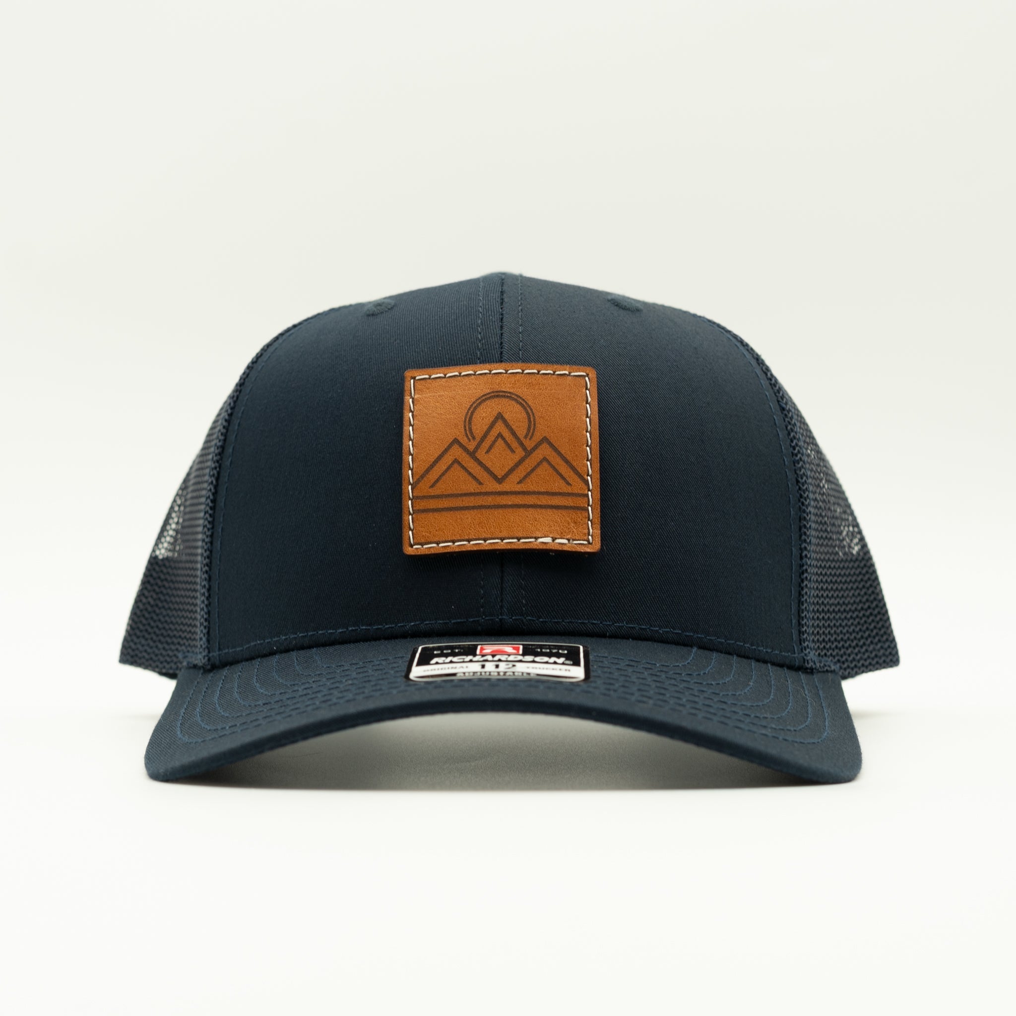 Front view of Lunar Ridge navy Richardson 112 trucker hat with veg tan leather mountain patch and curved visor
Color: Navy/Navy