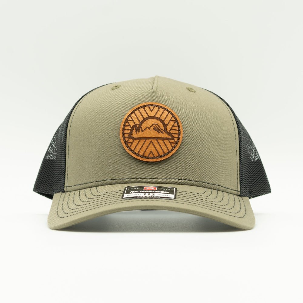 Front view of the Mosaic Sunset Leather Patch Hat by Outer Wings in loden/black, highlighting the structured mid-profile design of the Richardson 112FP. The side showcases the unique laser-engraved leather patch with the Mosaic Sunset design, adding a distinctive look to this custom leather patch hat. Ideal for outdoor adventures, the hat features a breathable mesh back and adjustable Snap-Back for comfort and versatility.
Color: Loden/Black