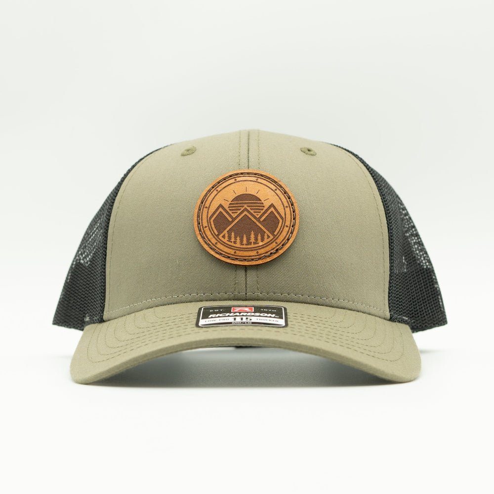 Front view of the Modern Mountains Leather Patch Hat in Loden/Black, showing the hat’s low-profile structure, pre-curved visor, and adjustable SnapBack. The leather patch features a modern mountains and sunset design, perfect for those who love the outdoors.
Color: Loden/Black