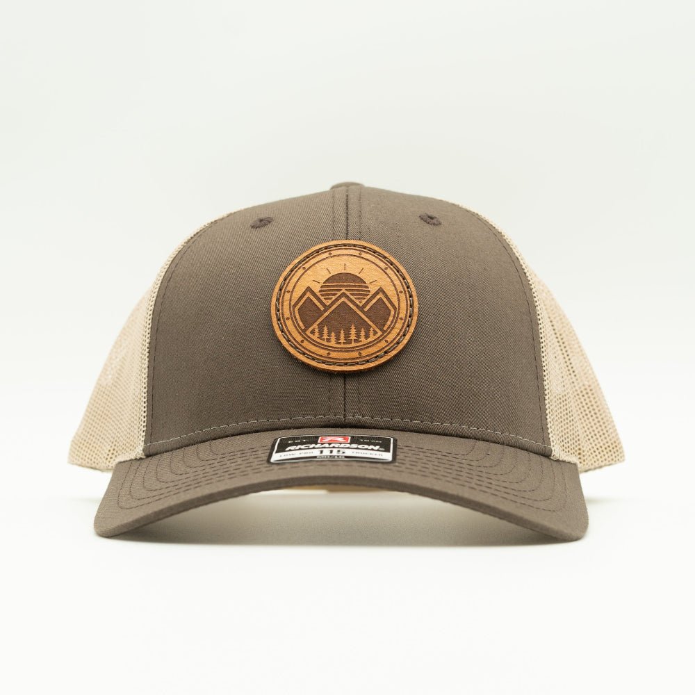 Front view of the Modern Mountains Leather Patch Hat in Brown/Khaki, highlighting the structured profile, breathable mesh back, and adjustable SnapBack closure. The genuine leather patch with a modern mountains and sunset design adds a distinctive touch to the hat’s style.
Color: Brown/Khaki