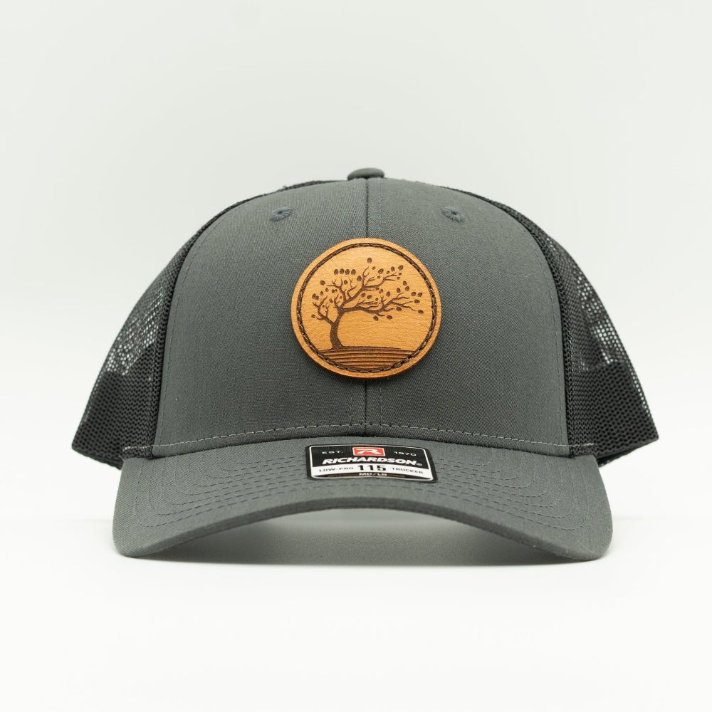 Front view of Charcoal Black Blossom leather patch hat on Richardson 115, structured low profile crown and curved visor.
Color: Charcoal/Black