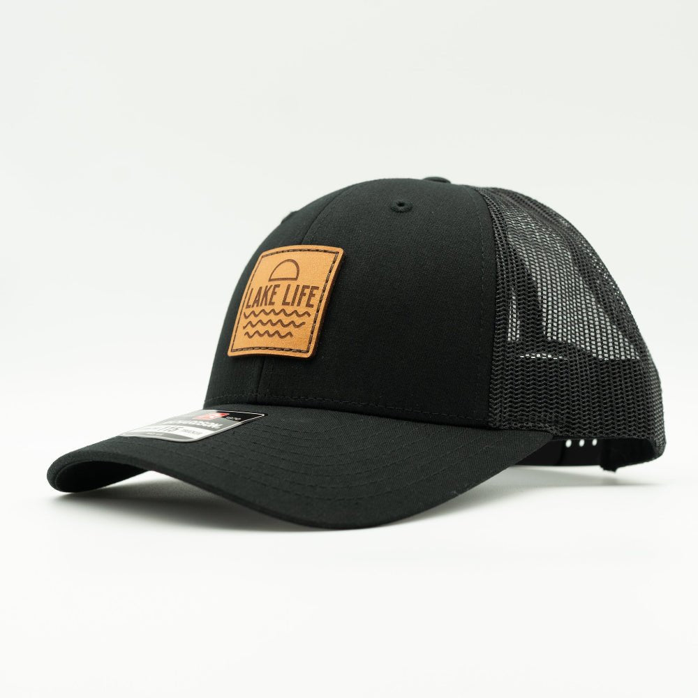 Side view of Lake Life leather patch hat on black and black Richardson 115 low profile trucker, showing shallow crown, leather patch, curved bill, and mesh back.
Color: Solid Black