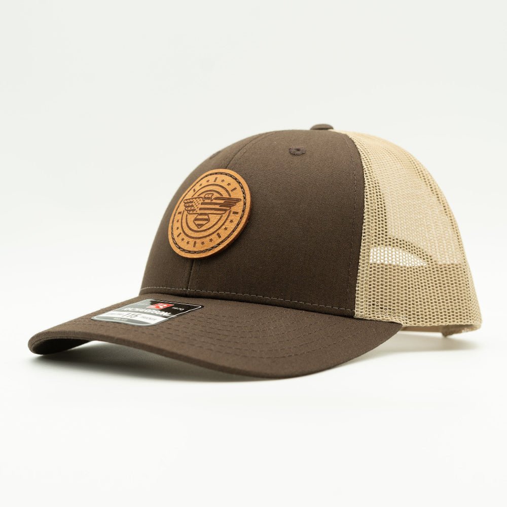 Side view of brown and khaki Richardson 115 low profile trucker hat with American Eagle leather patch, showing brown front panel, curved bill, and light khaki mesh back.
Color: Brown/Khaki