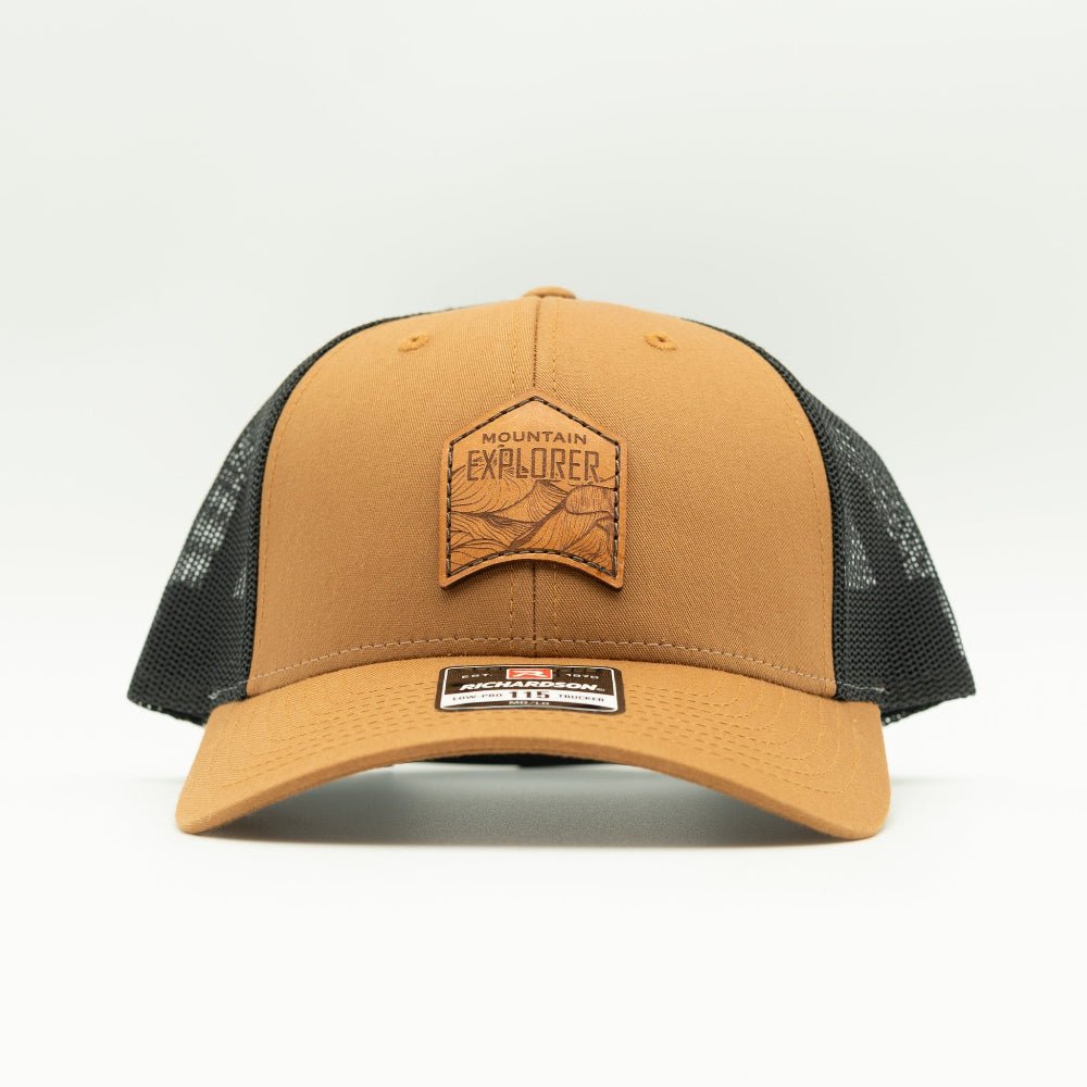 Front view of caramel and black Mountain Explorer leather patch low profile hat, Richardson 115 trucker with sewn full-grain leather mountain patch for rugged outdoors wear