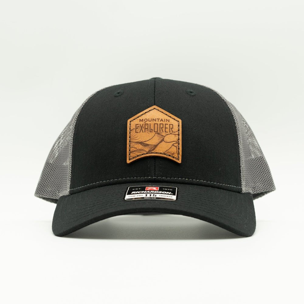 Front view of black and charcoal Mountain Explorer leather patch low profile hat, real veg-tan leather mountain patch on Richardson 115 trucker for everyday trail wear.