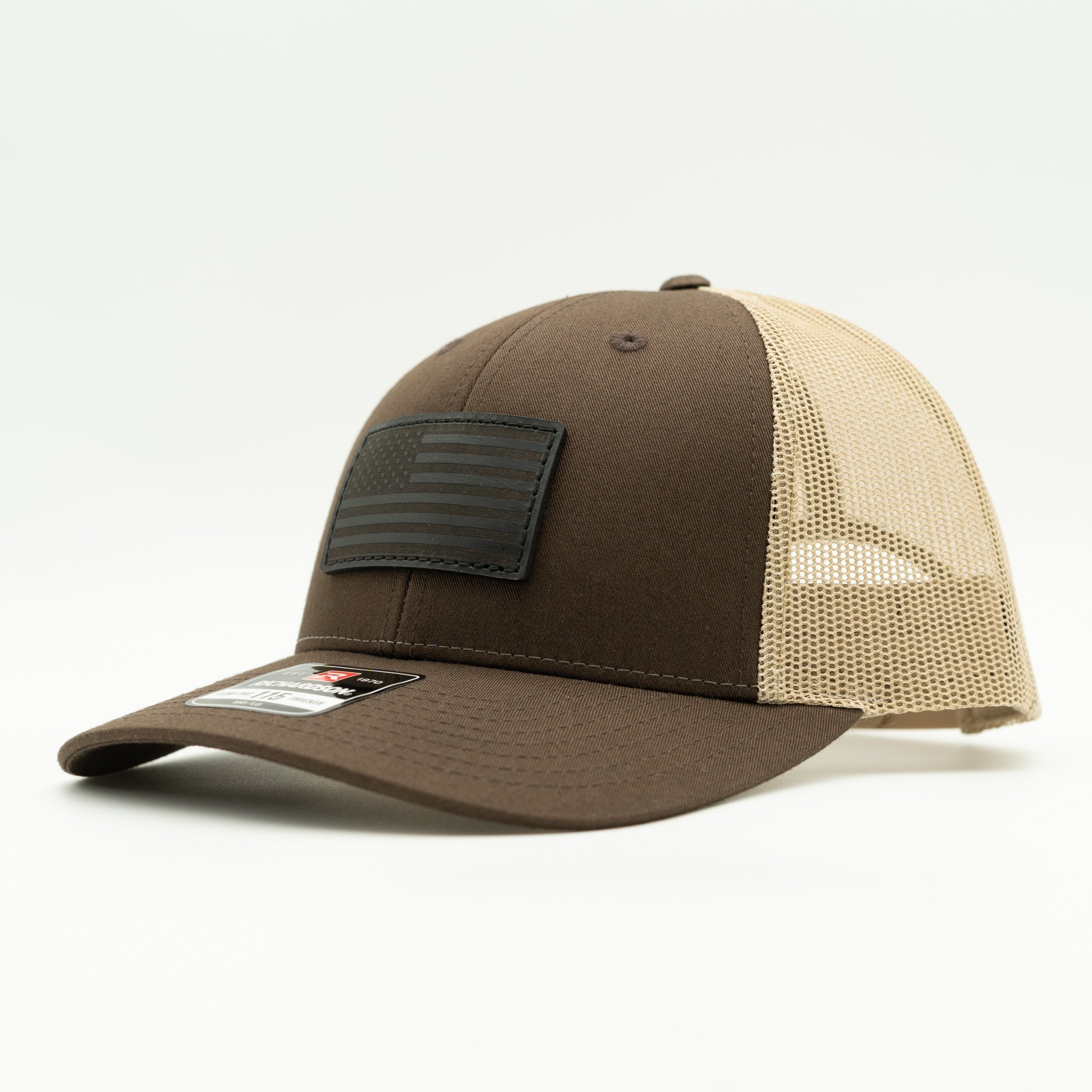 A brown and beige trucker cap with a dark brown rectangular American flag patch on the front, shown on a clean white background.
Color: Brown/Khaki