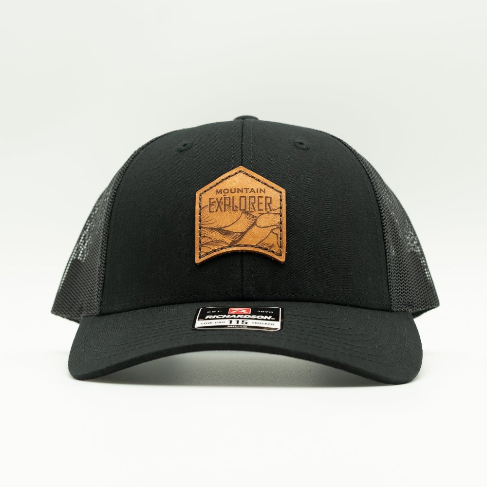Front view of black Mountain Explorer leather patch hat on Richardson 115 low profile trucker, sewn real leather mountain patch and breathable mesh back for Colorado adventures