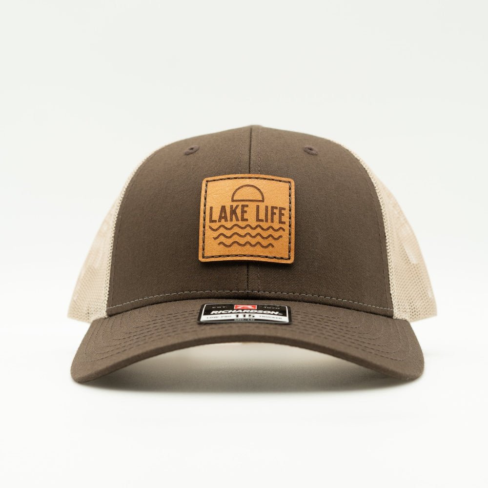 Front view of Lake Life leather patch hat on brown and khaki Richardson 115 low profile trucker, showing leather patch, curved bill, light mesh back, and snapback.
Color: Brown/Khaki