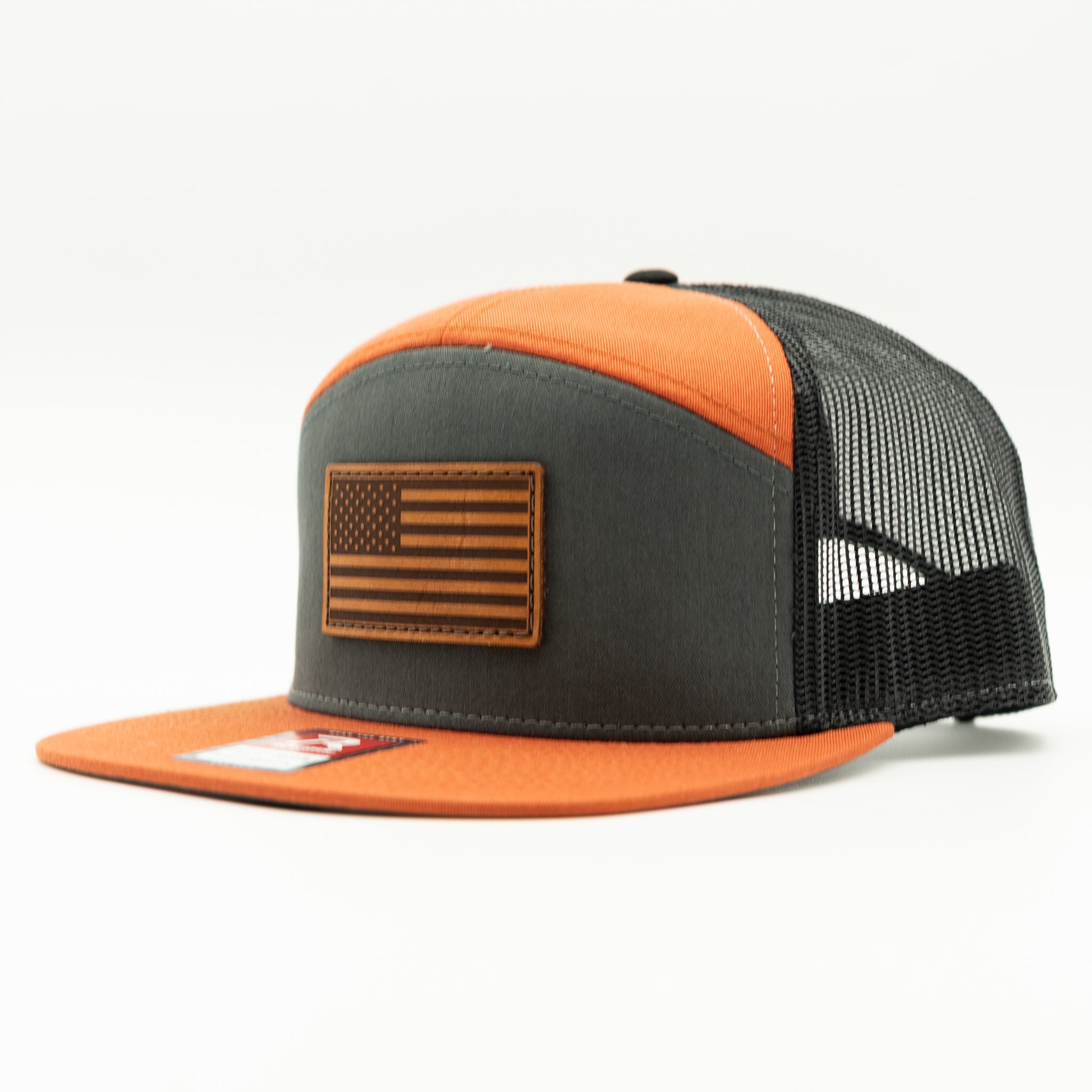 Charcoal, orange, and black Richardson 168 seven panel flat bill trucker hat with light brown American Flag leather patch, side view showing orange bill and mesh back.
Color: Charc/Orange/Black 168 (OSFM)