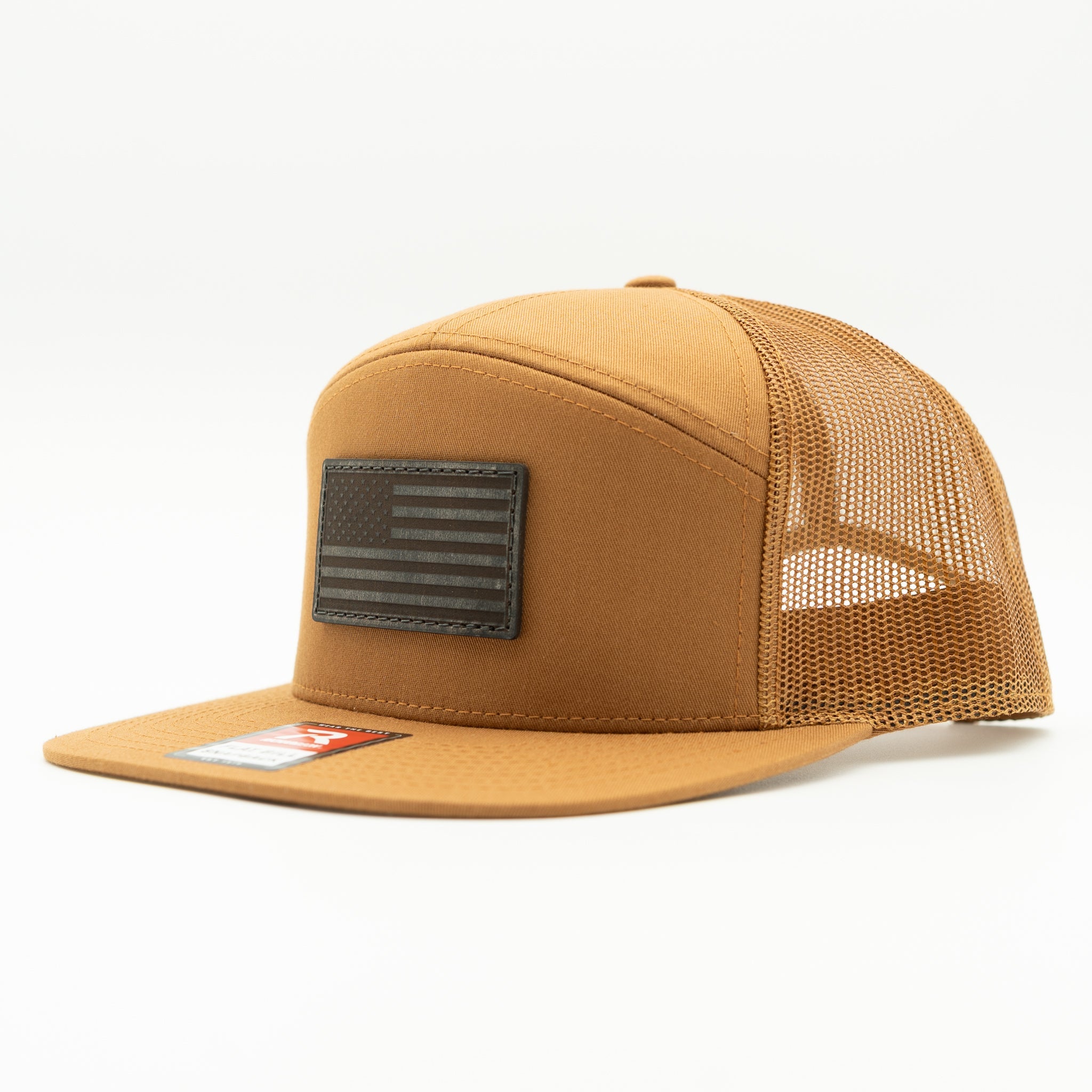Caramel Richardson 168 flat bill trucker hat with charcoal American Flag leather patch, side view highlighting seven panel shape and mesh back.
Color: Caramel 168 (OSFM)