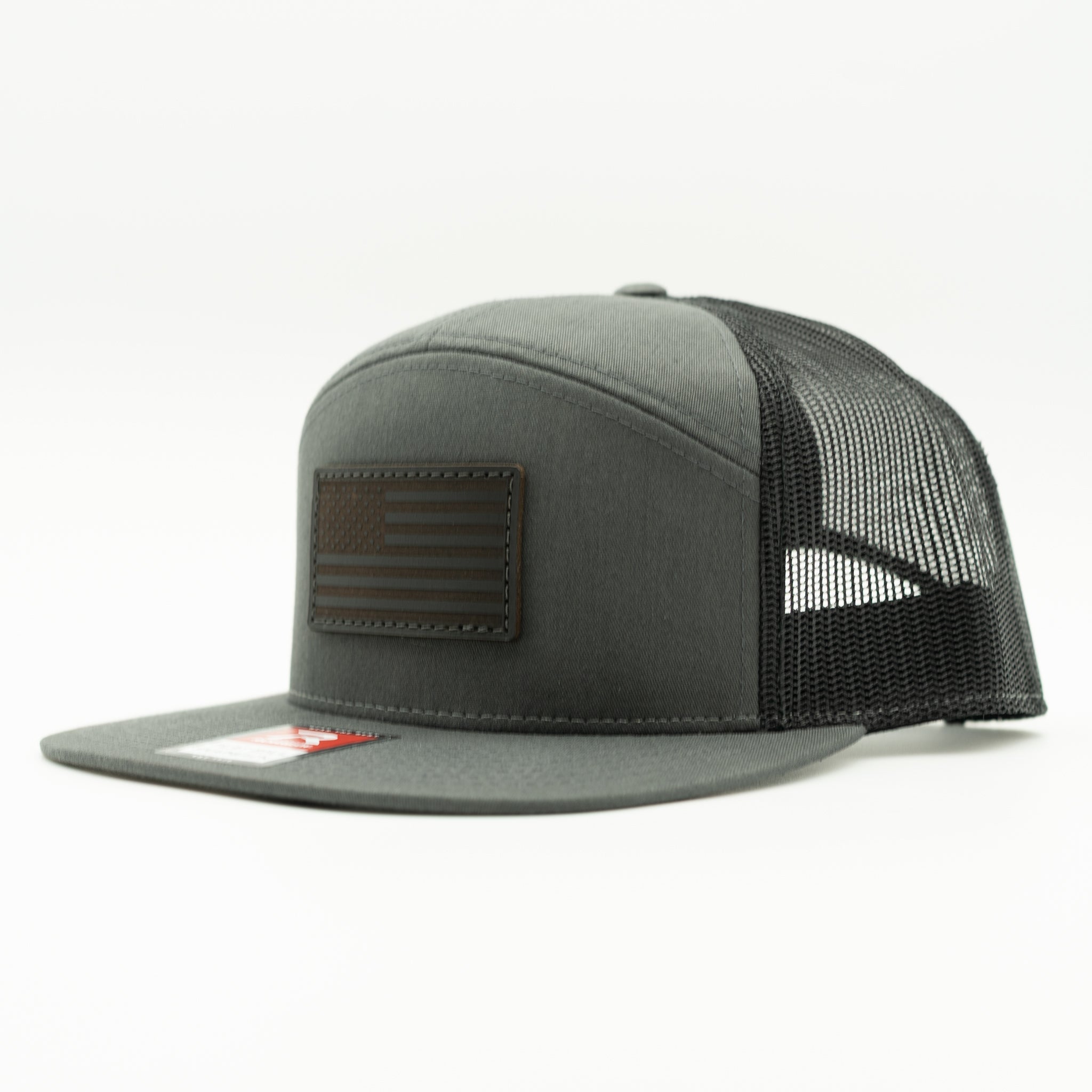 Charcoal and black Richardson 168 seven panel trucker hat with black American Flag leather patch, side view showing structured crown and flat bill.
Color: Charcoal/Black 168 (OSFM)