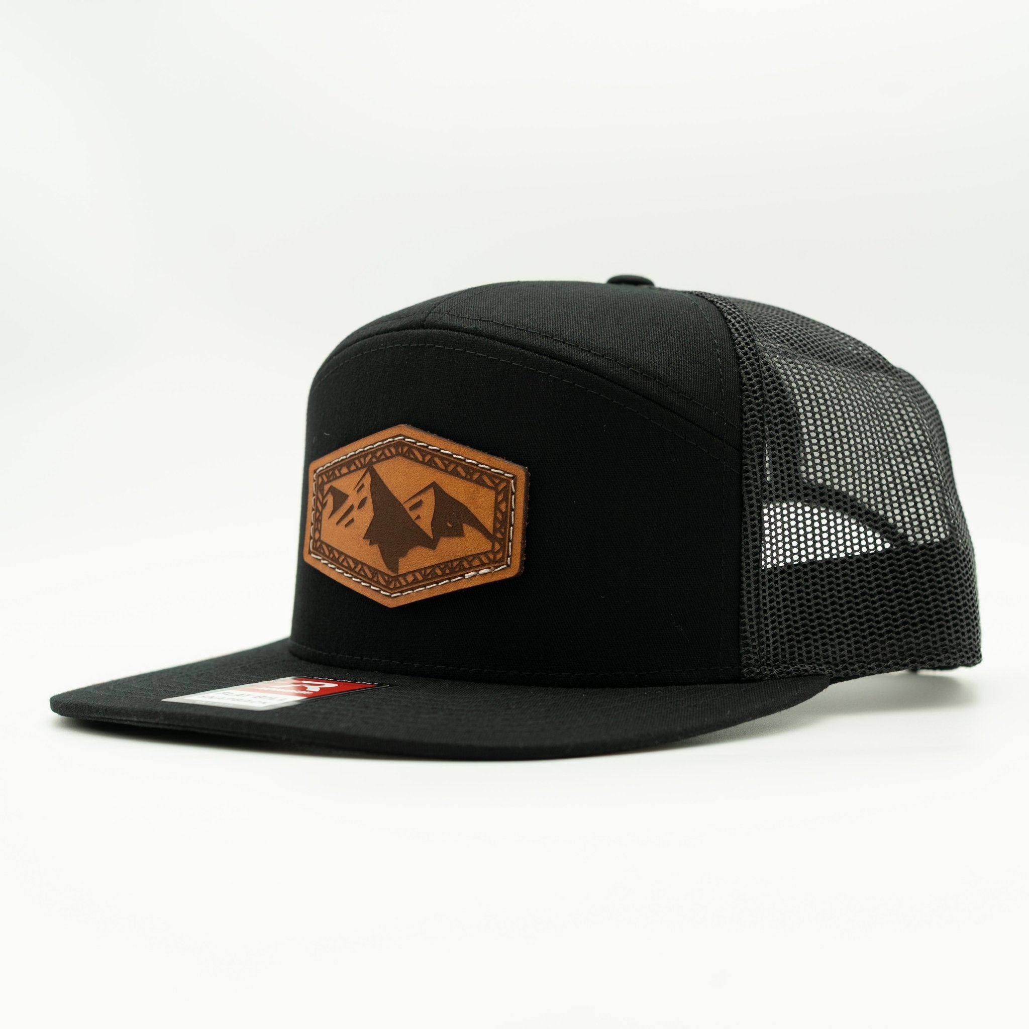 Black trucker cap with a brown leather patch featuring mountain designs on a white background
Color: Black/Black 168 (OSFM)
