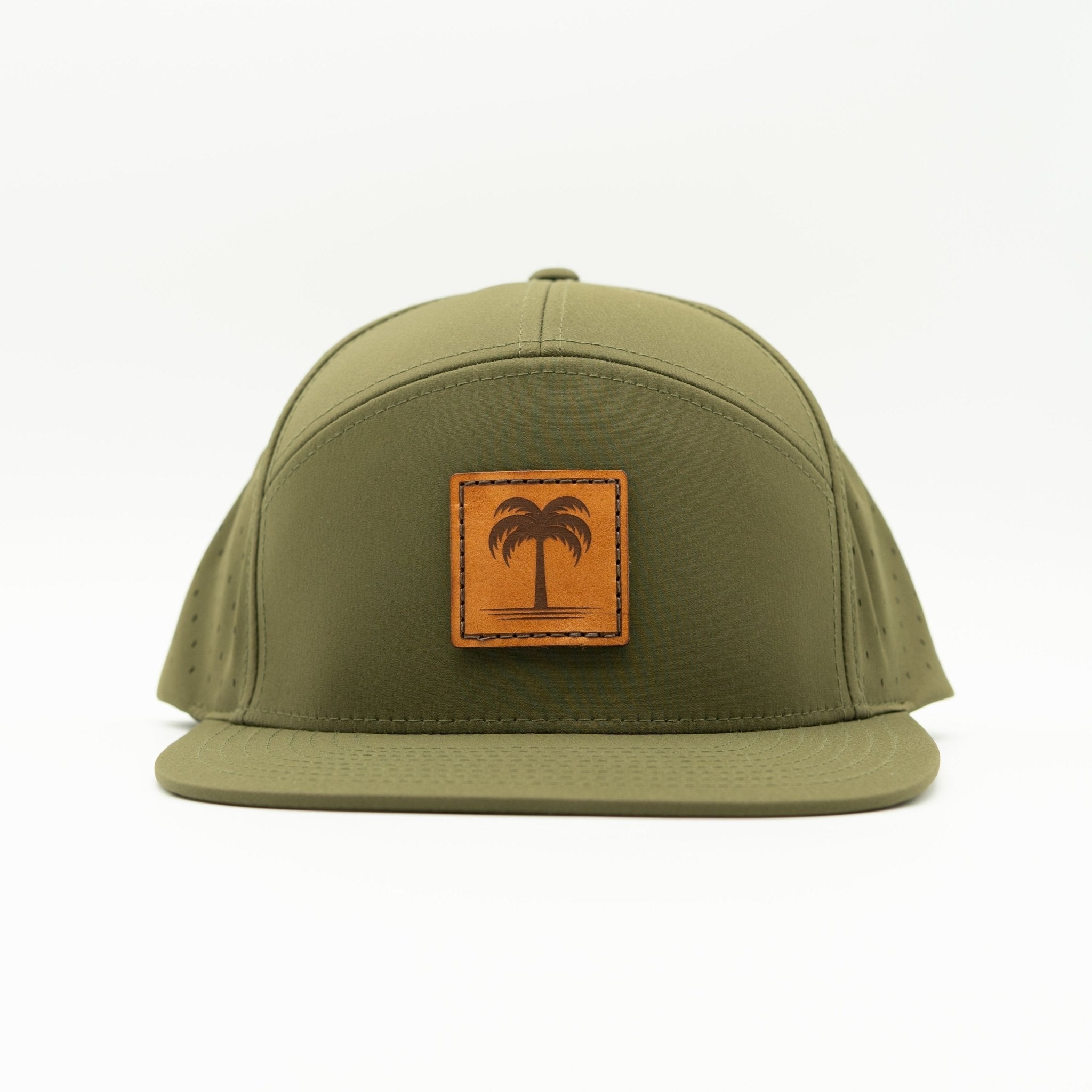 An olive green flat-brim cap with a square tan leather patch on the front featuring an embossed palm tree design, set against a plain white background.
Color: Olive