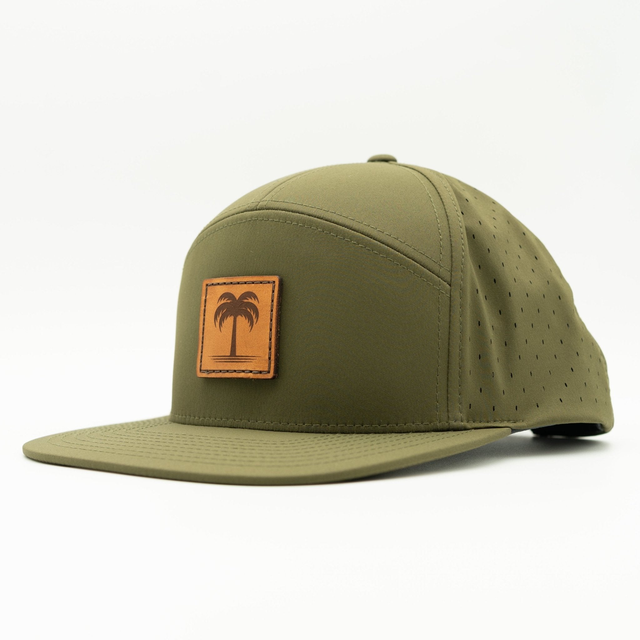 An olive green flat-brim cap with a tan rectangular patch on the front featuring a black palm tree logo, photographed on a clean white background.
Color: Olive