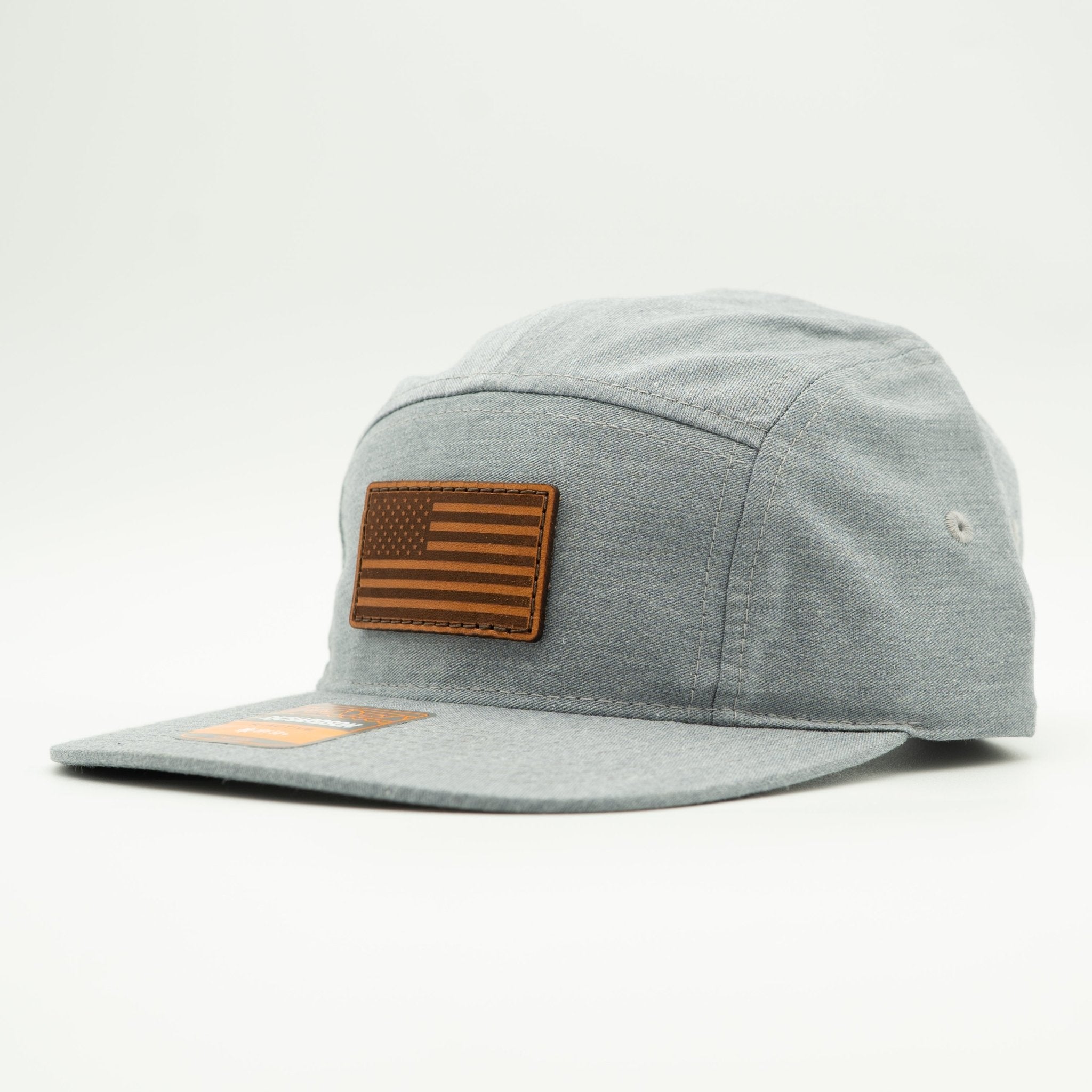 A light gray heathered 5-panel cap with a brown leather American flag patch on the front, set against a plain light gray background.
Color: Heather Grey