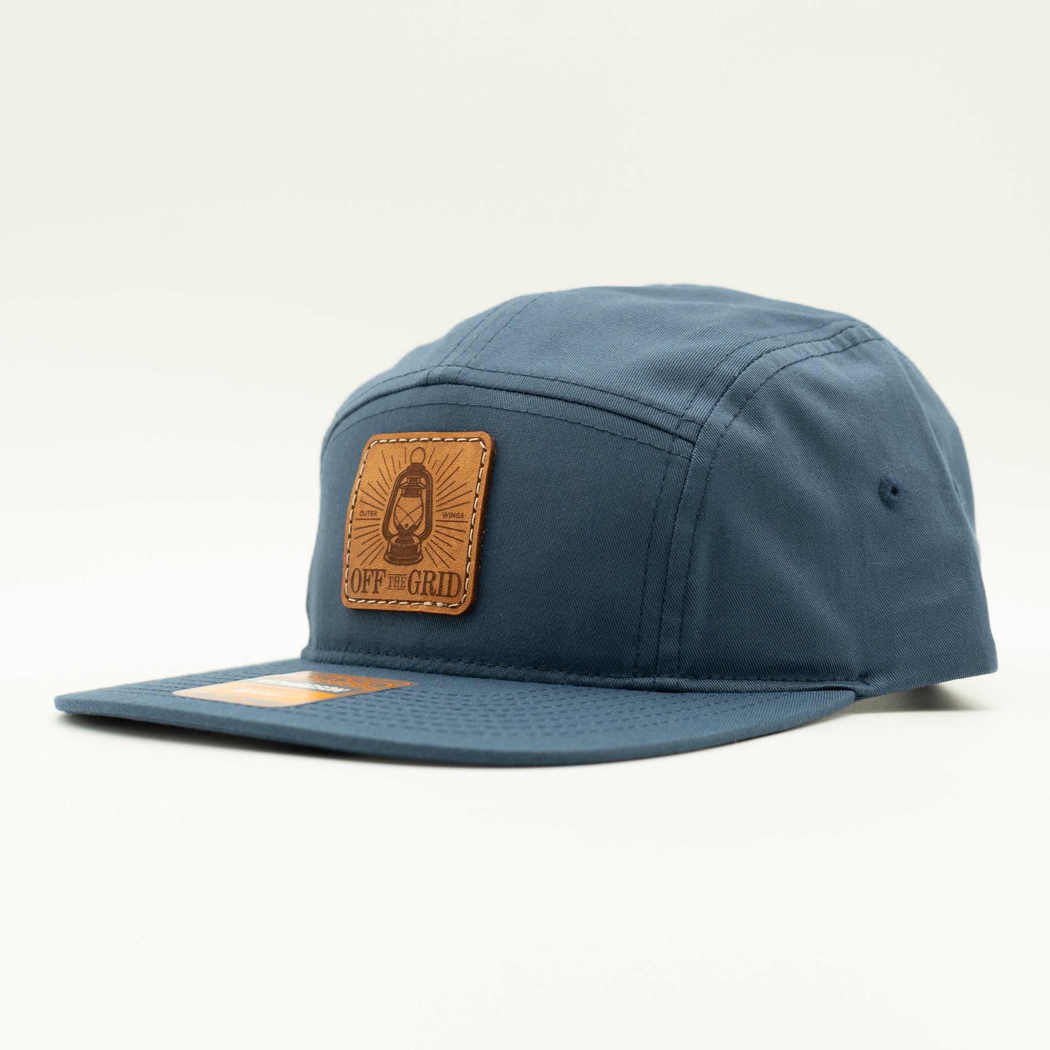 Light navy Off The Grid Richardson 217 camper hat side view, blue leather patch camper hat with flat bill for hikers and travelers.