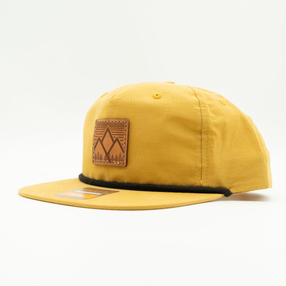 Side view of biscuit Richardson 256 Mountain West rope hat, showing veg-tanned leather mountain patch, flat bill with rope, and lightweight cotton-nylon fabric.