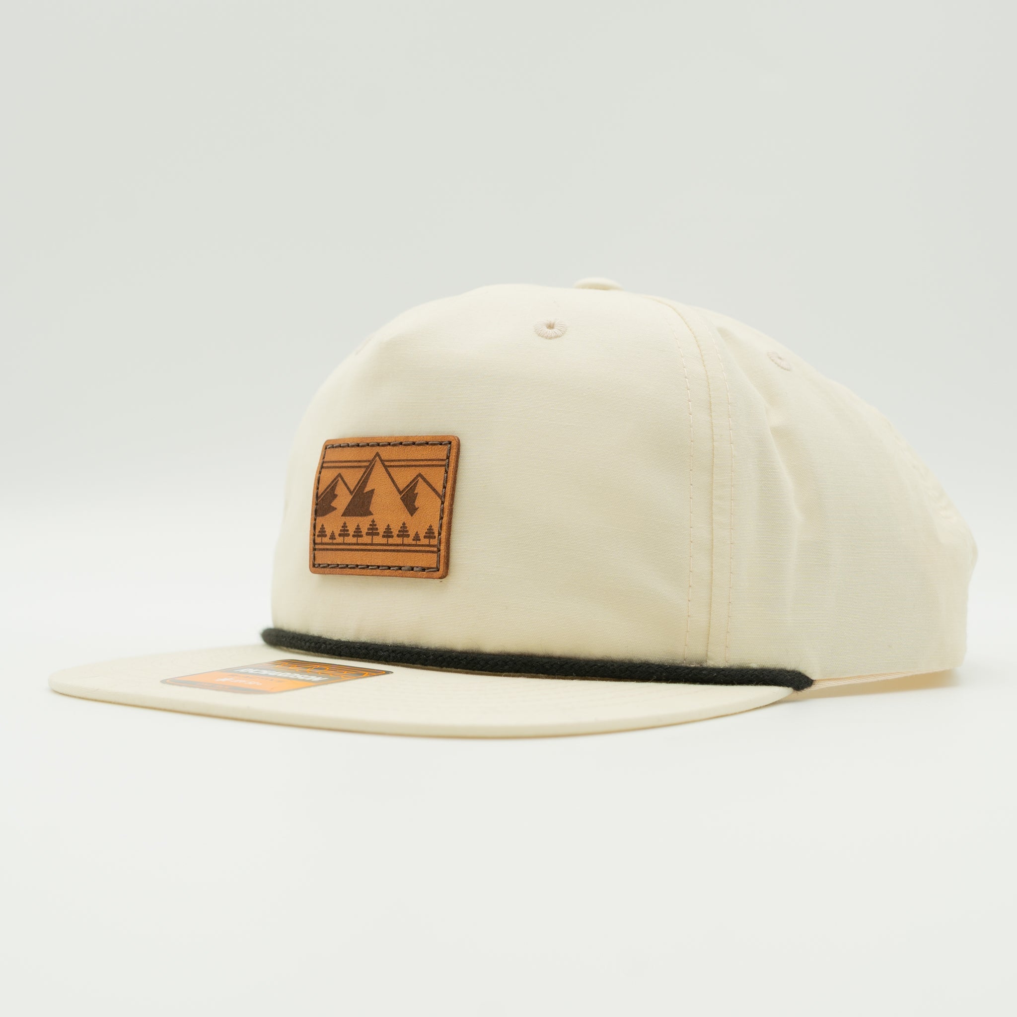 Side view of birch Richardson 256 Ridgeline mountain rope hat, showing leather mountain patch, flat bill with rope, low profile 5-panel crown, and snapback.