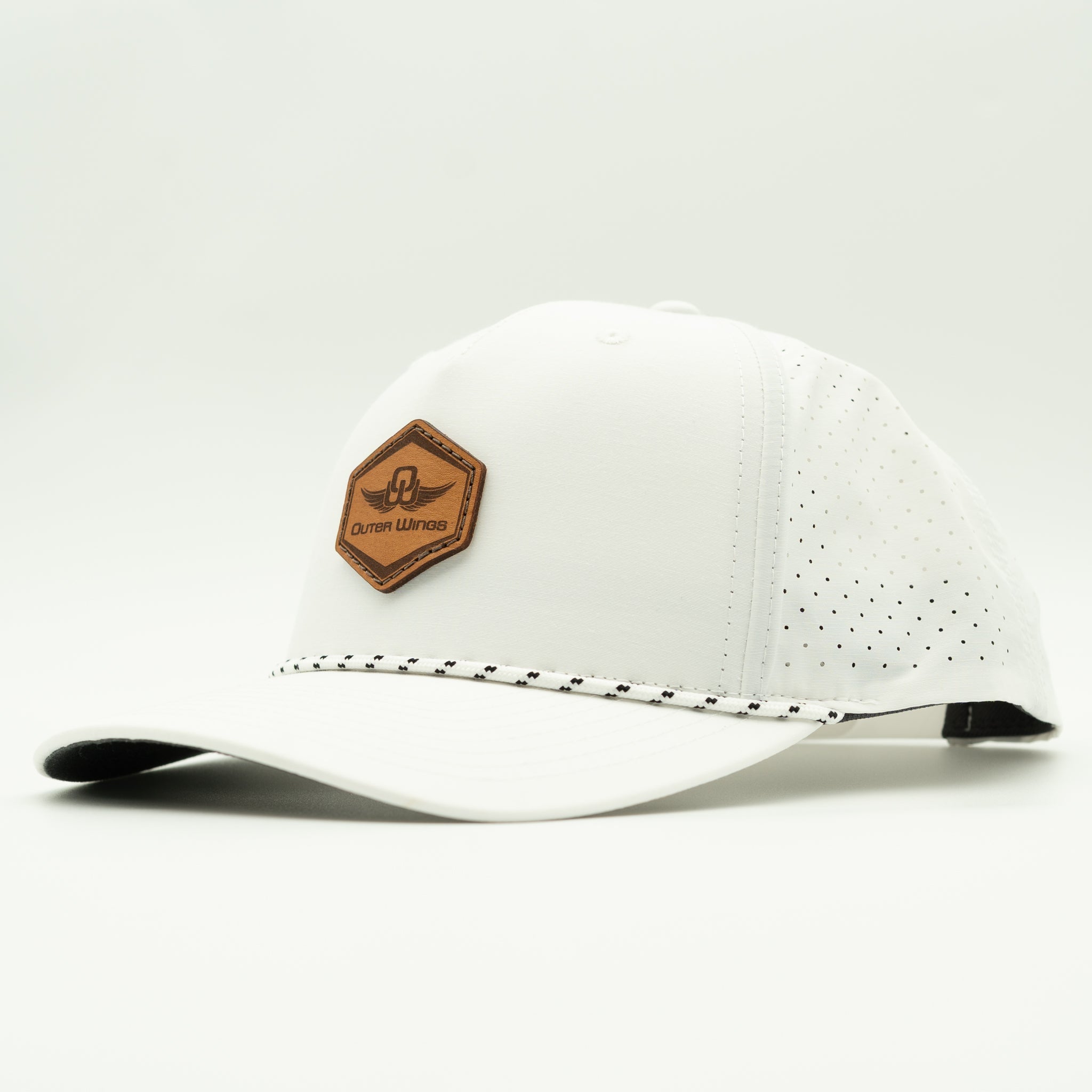 A white baseball cap with perforated side panels, a brown hexagonal leather patch on the front, and a decorative black-and-white stitched line across the brim, shown on a light gray background.
Color: Solid White