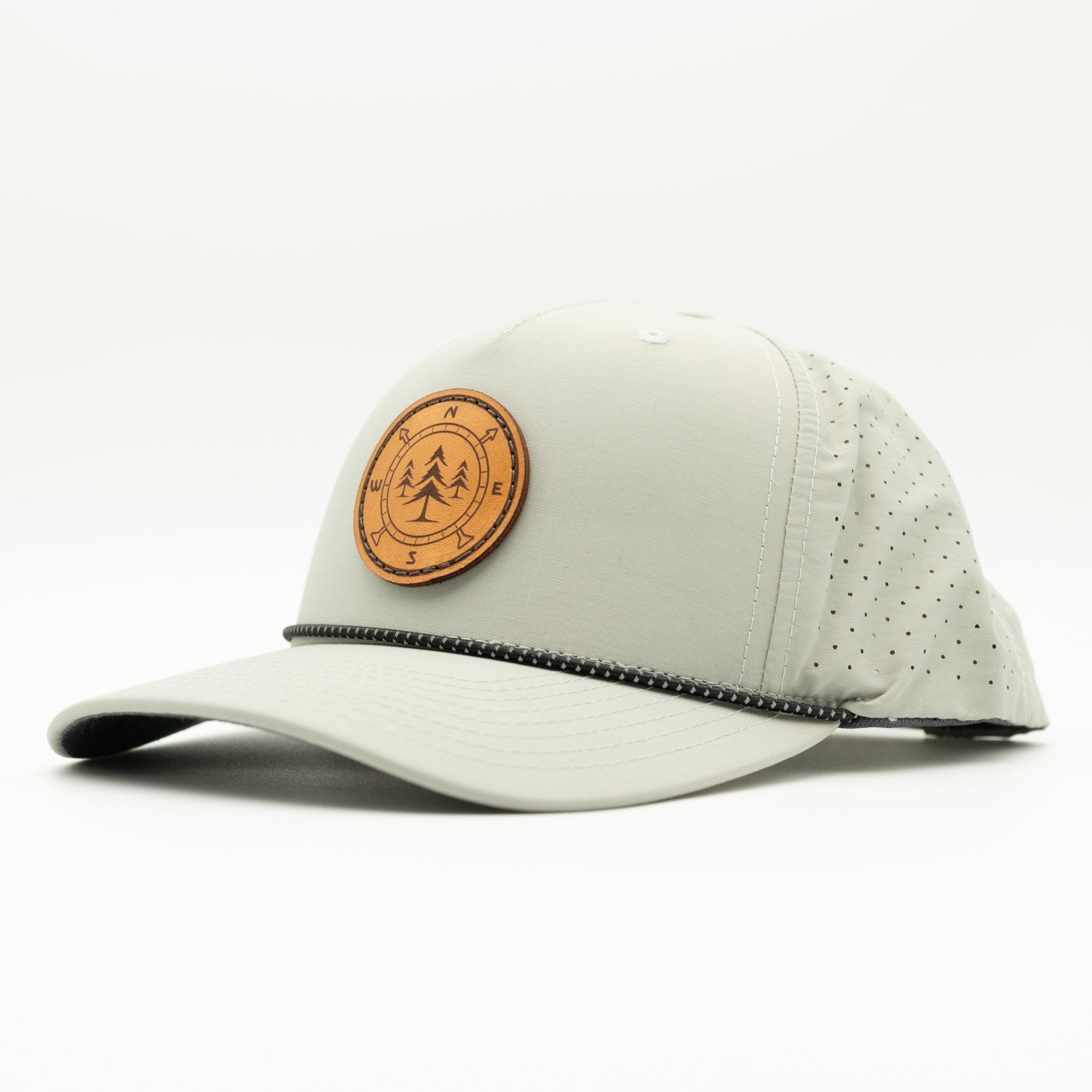 A light gray outdoor cap with a curved brim, perforated back panels, and a circular brown leather patch on the front featuring a tree logo.
Color: Silver