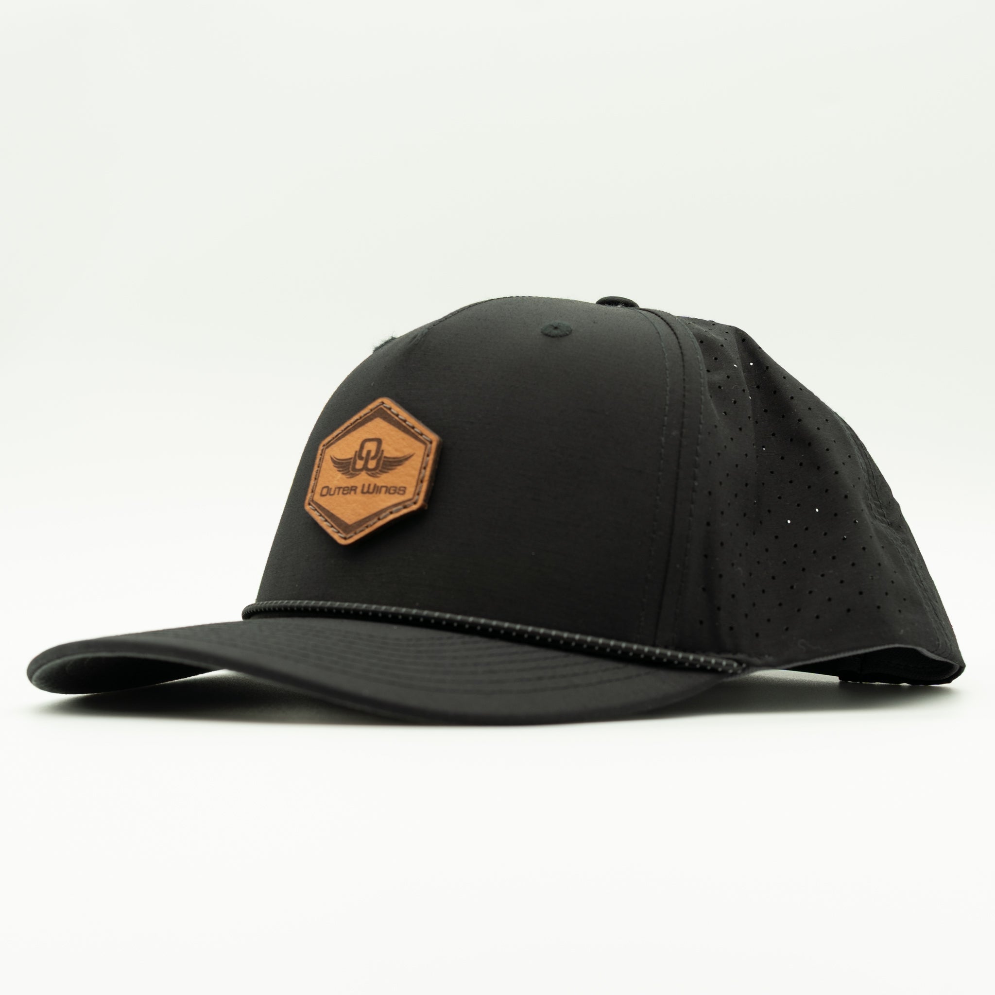 A black baseball cap with a curved brim, featuring a brown leather hexagonal patch on the front with the brand name 'Outer Wings'.. The cap has perforated side panels and is photographed on a clean white background.
Color: Black