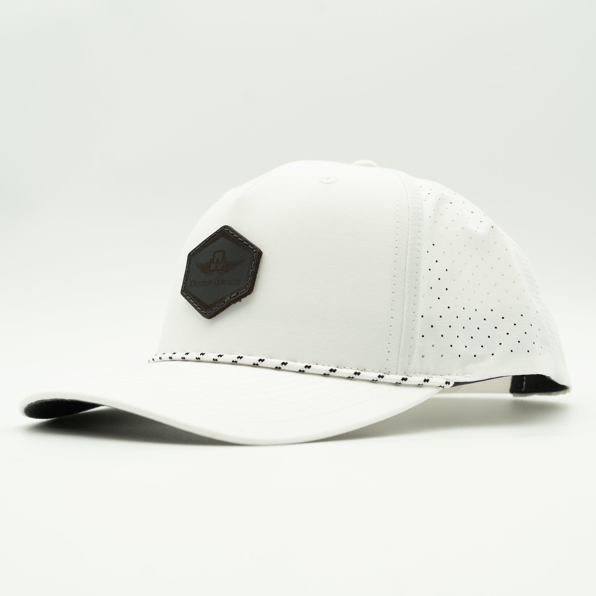 A white structured baseball cap with perforated side panels, a black hexagonal patch on the front, and a black-and-white dotted trim along the edge of the brim, shown on a light gray background.
Color: Solid White
