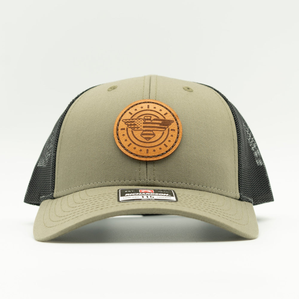 Front view of loden and black Richardson 115 low profile trucker hat with round American Eagle and flag leather patch, curved visor, and black mesh back.

Color: Loden/Black