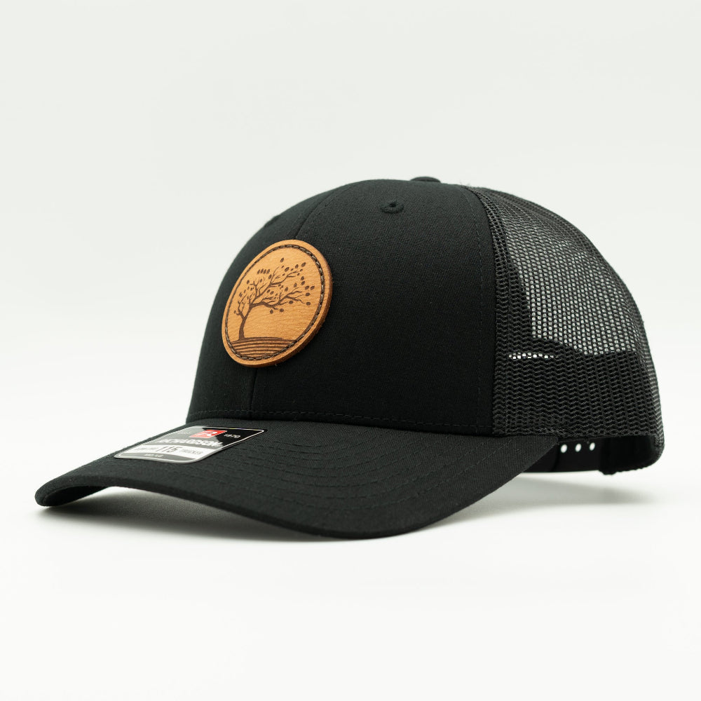 Side view of the Blossom Leather Patch Hat by Outer Wings in black/black, highlighting the hat’s low-profile structure, comfortable fit, and the distinctive Blossom leather patch. The adjustable SnapBack and real leather patch make it a perfect choice for any occasion.