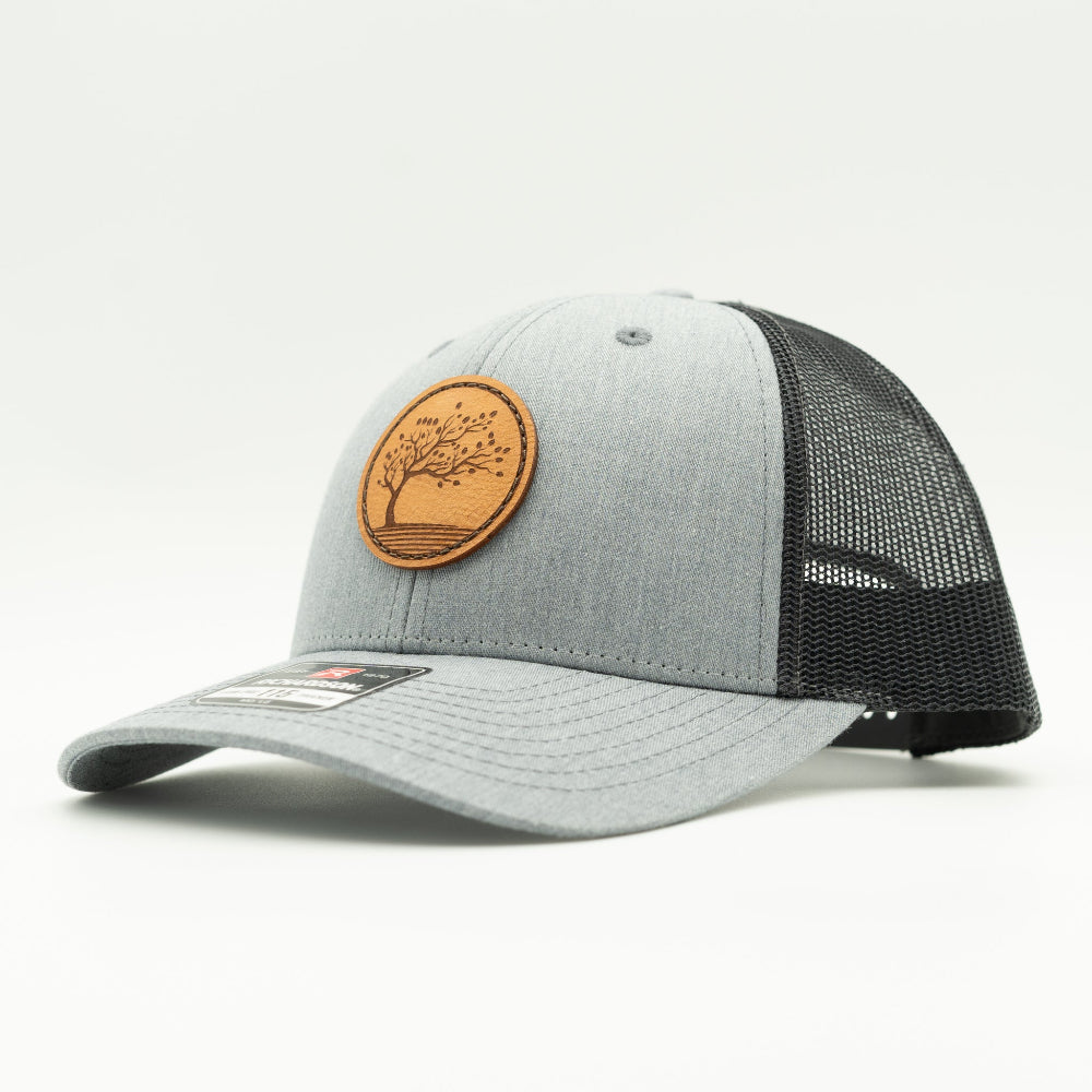 Side view of the Blossom Leather Patch Hat by Outer Wings in heather grey/dark charcoal, highlighting the hat’s low-profile design, comfortable fit, and adjustable SnapBack. The Blossom leather patch adds a unique, elegant touch to this versatile hat.