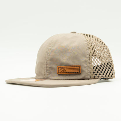 Side view of the Khaki Fast Bike Hat, showing the wide-set mesh back and adjustable quick-adjust pack webbing, with the Fast Bike leather patch visible from the side.