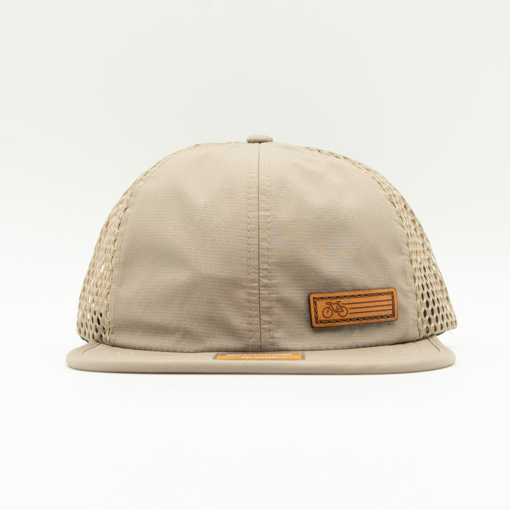 Front view of the Khaki Fast Bike Hat, showing the wide-set mesh back and adjustable quick-adjust pack webbing, with the Fast Bike leather patch visible from the side.