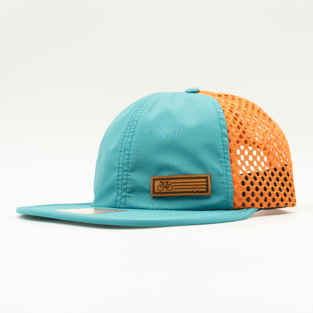 Side view of the Teal Fast Bike Hat, displaying the vibrant orange accents and wide-set mesh back, with the Fast Bike leather patch visible from the side.