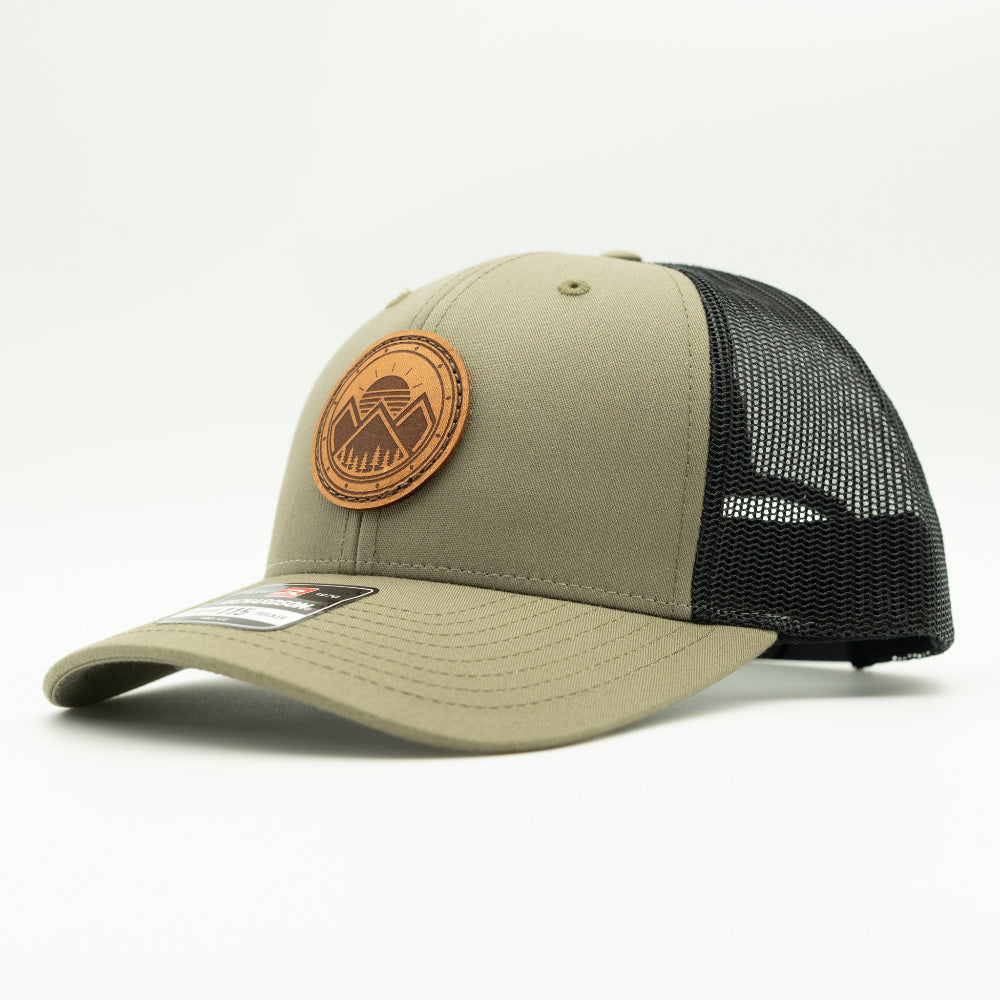 Side view of the Modern Mountains Leather Patch Hat in Loden/Black, showing the hat’s low-profile structure, pre-curved visor, and adjustable SnapBack. The leather patch features a modern mountains and sunset design, perfect for those who love the outdoors.