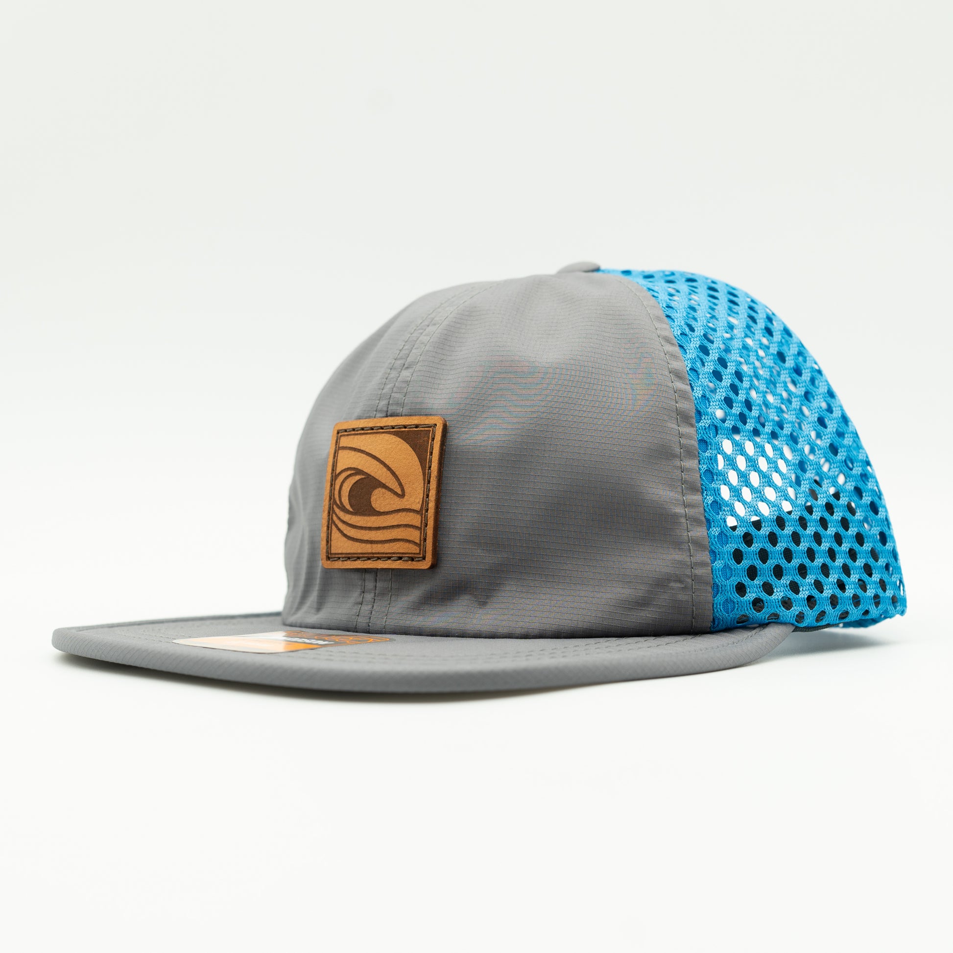 Side view of the Ocean Swell Hat by Outer Wings in Charcoal/Cyan, highlighting the wide-set mesh back, adjustable webbing backstrap, and flex packable visor. A functional and stylish performance hat for all-day comfort.