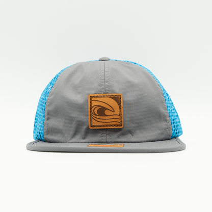 Front view of the Ocean Swell Hat by Outer Wings in Charcoal/Cyan, highlighting the wide-set mesh back, adjustable webbing backstrap, and flex packable visor. A functional and stylish performance hat for all-day comfort.