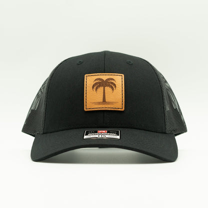 Front view of the Solo Palm Leather Patch Hat by Outer Wings in Black/Black, highlighting the breathable mesh back, structured profile, and adjustable SnapBack closure. A durable and stylish custom leather patch hat for outdoor and casual wear.