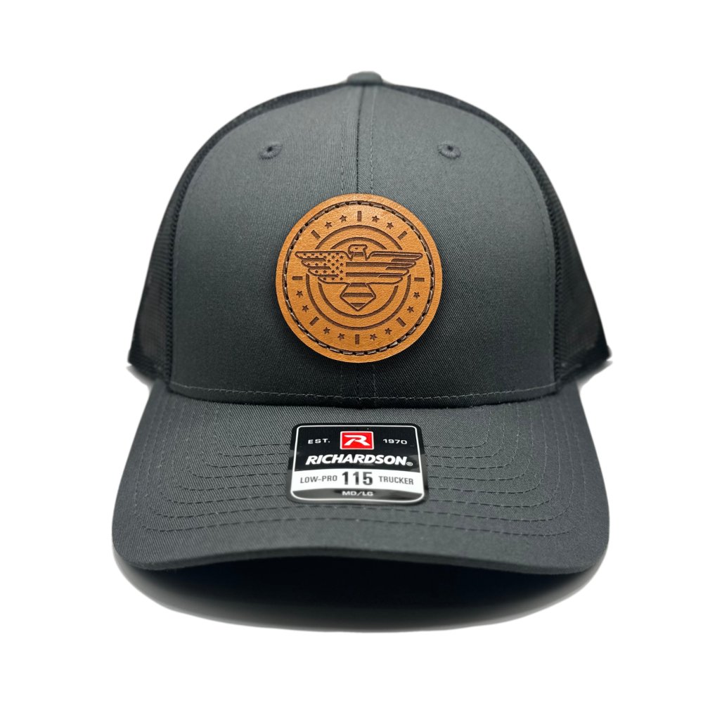 Front view of the American Eagle Design leather patch hat by Outer Wings in charcoal/black, featuring a low-profile Richardson 115 hat with a distinctive leather patch of an eagle, American flag, stars, and stripes. The charcoal front paired with a black mesh back adds a bold, contrasting look.